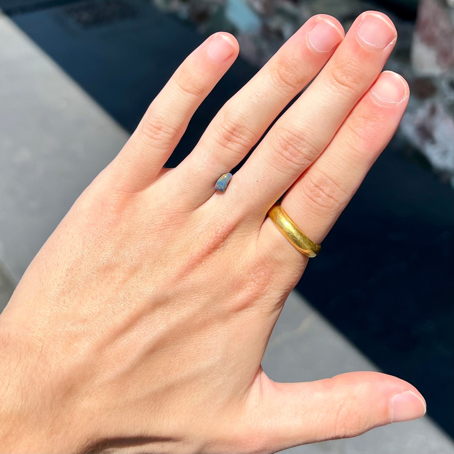 A freeform shaped black opal stone from Lightning Ridge, Australia.
