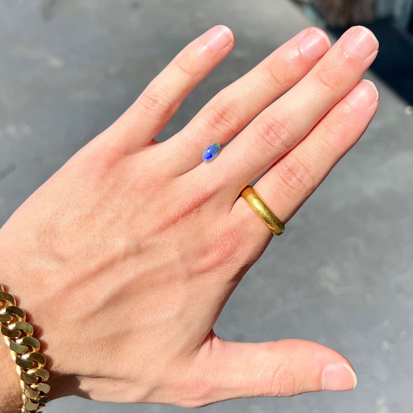 A loose, pill shaped black opal stone from Lightning Ridge, Australia. The opal is green and blue.
