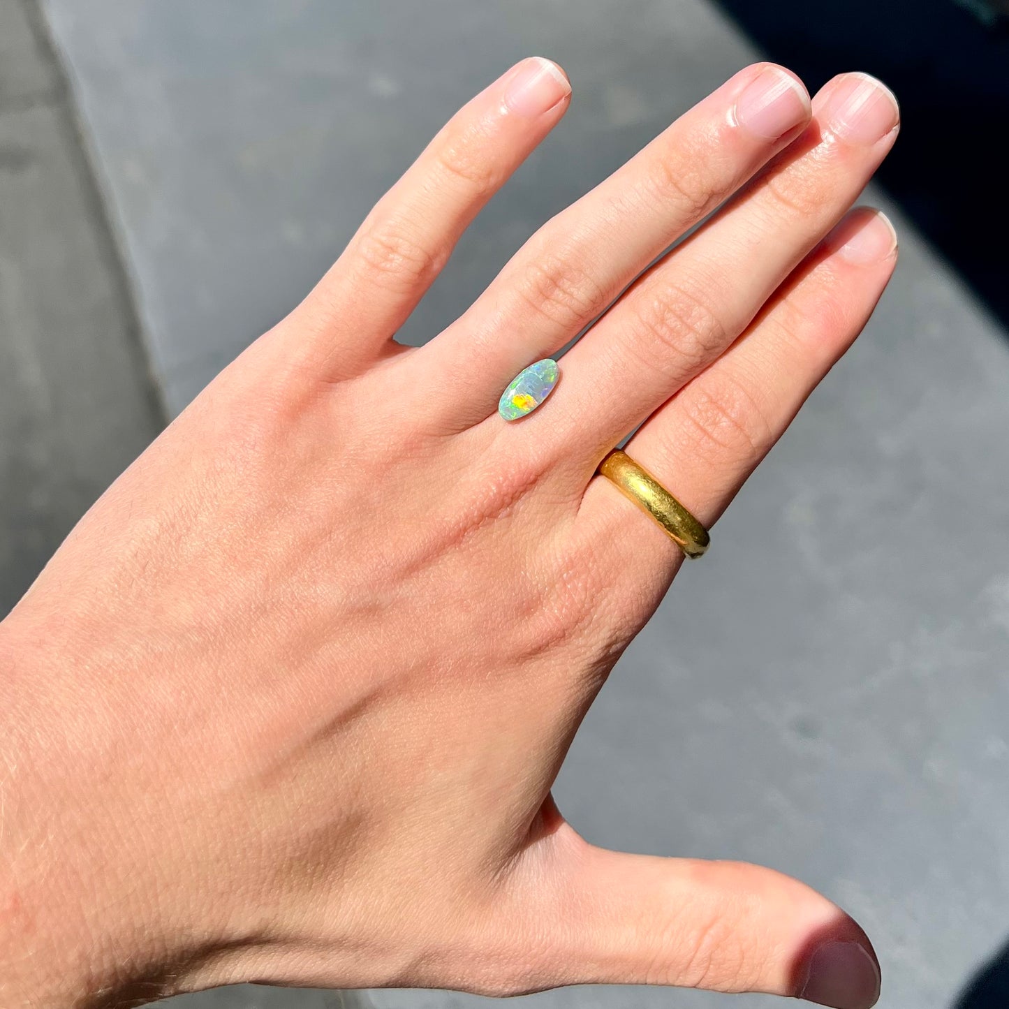 A loose, oval cabochon cut semi-black opal from Lightning Ridge, Australia. The opal plays green and orange colors.