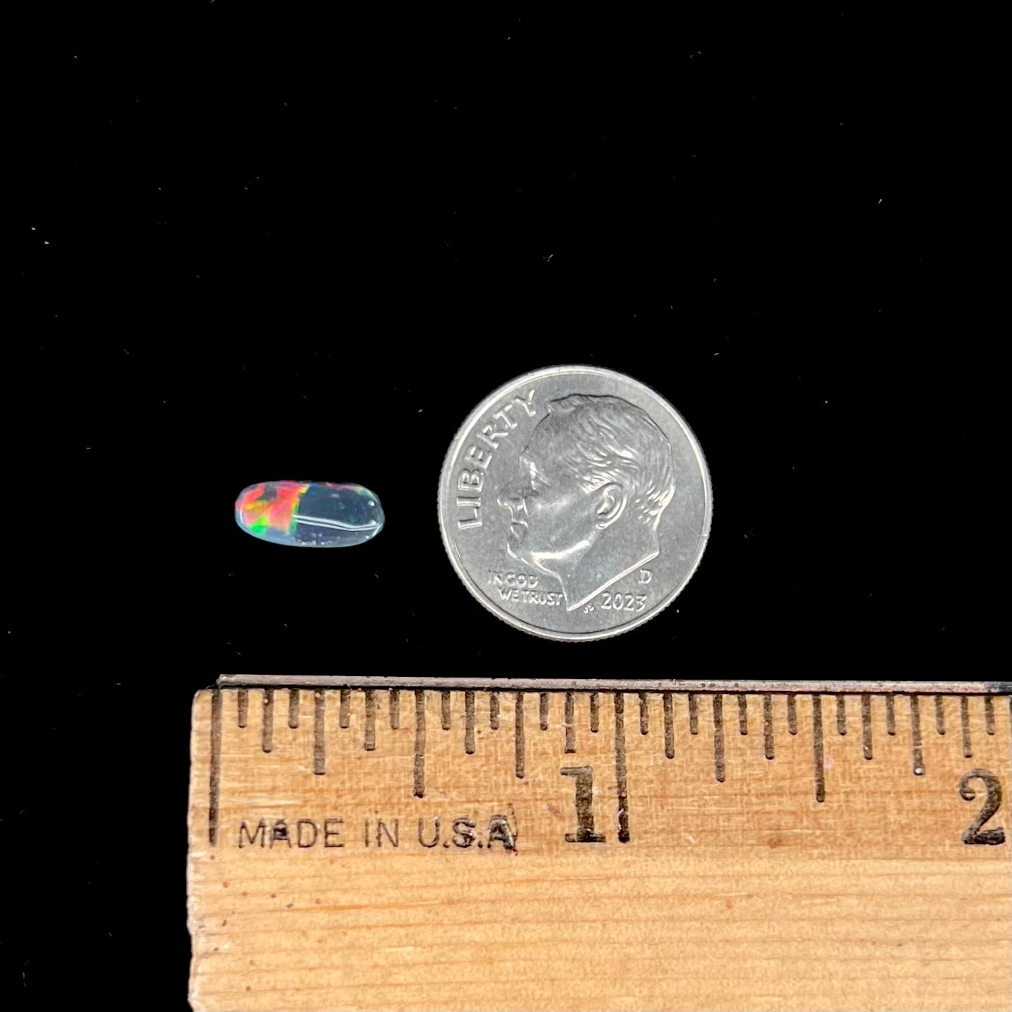 A loose black opal from Lightning Ridge, Australia.  The opal shines colors of red, green, and blue.