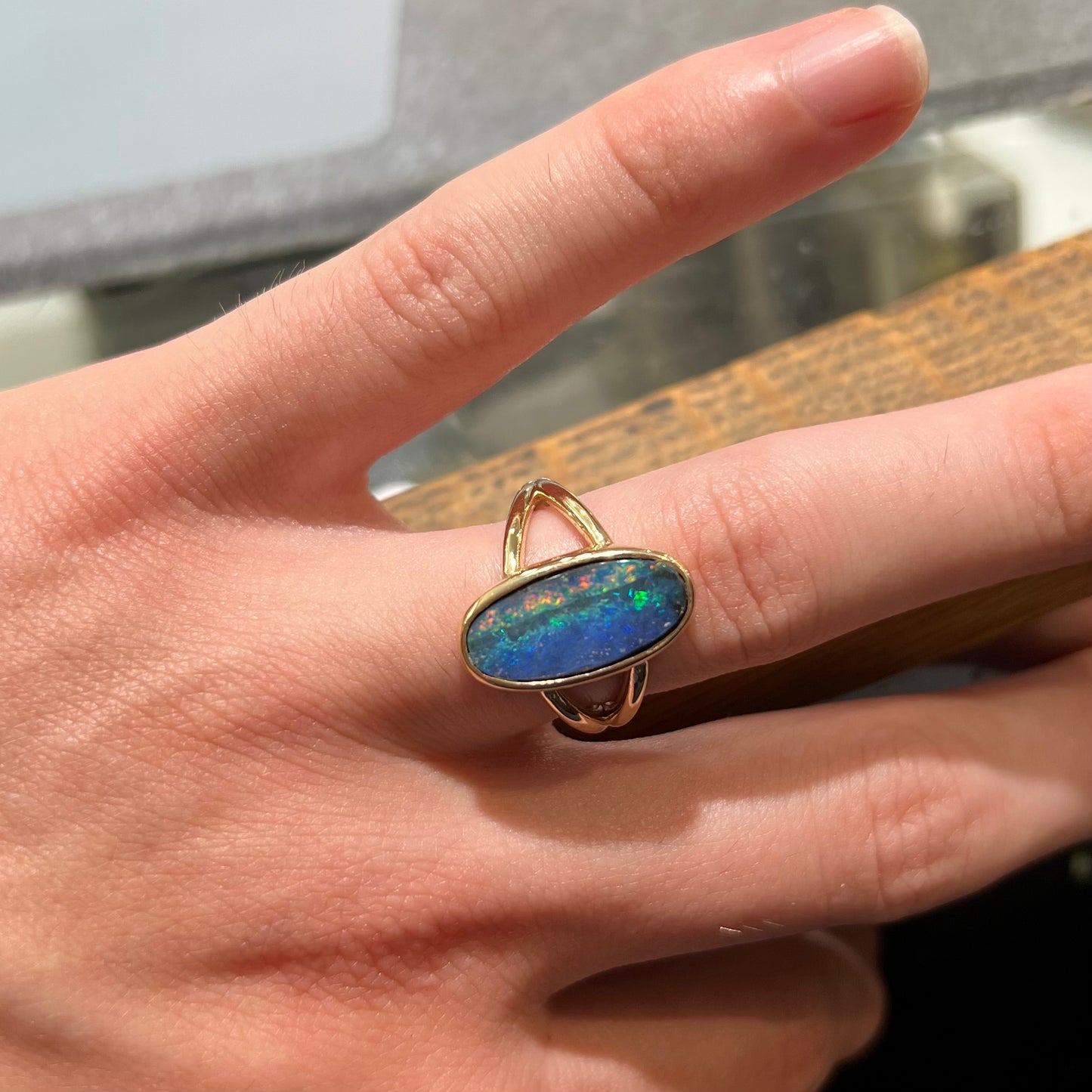 A ladies' yellow gold split shank solitaire ring set with a natural Australian black boulder opal.