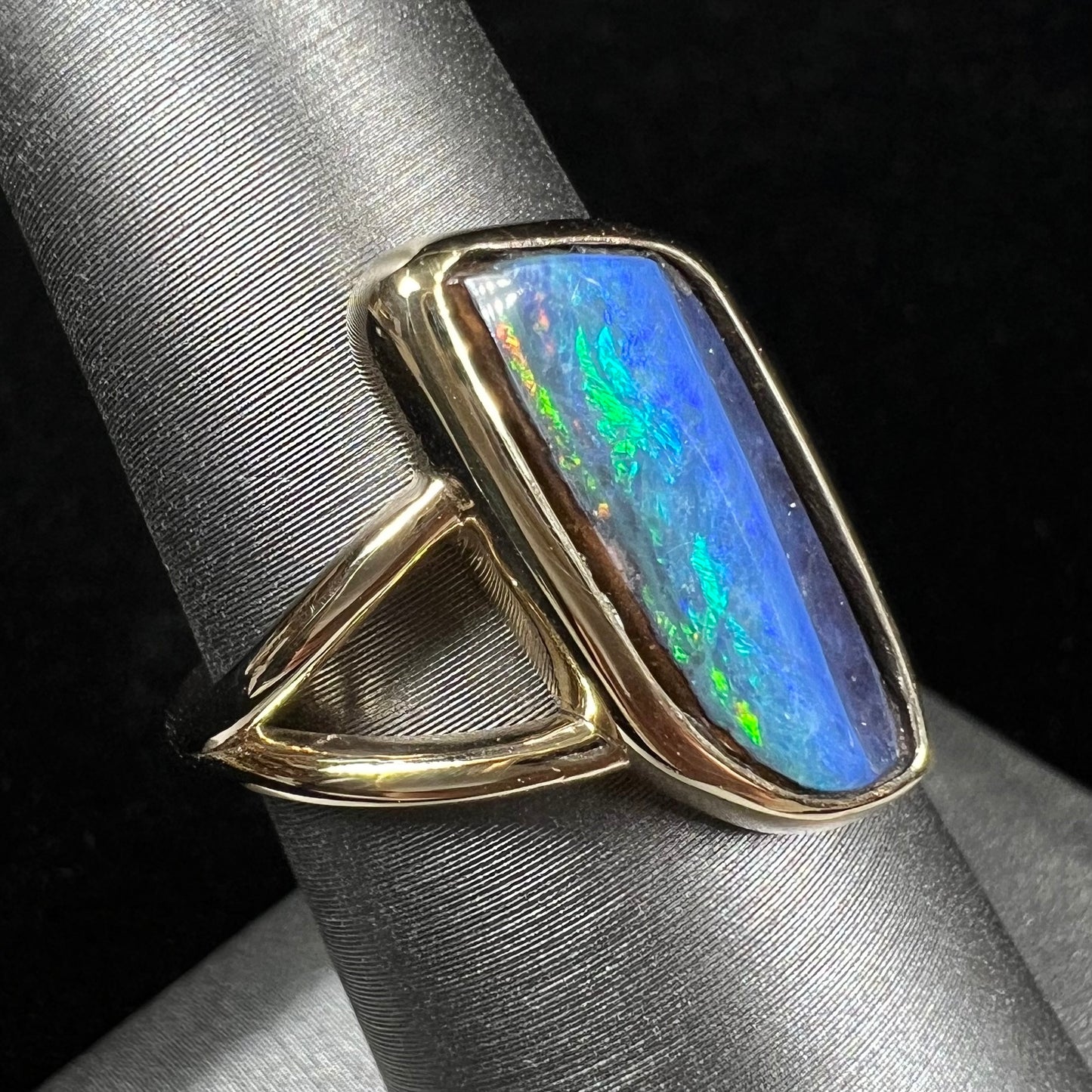 A ladies' split shank gold ring bezel set with a natural, Australian black boulder opal.