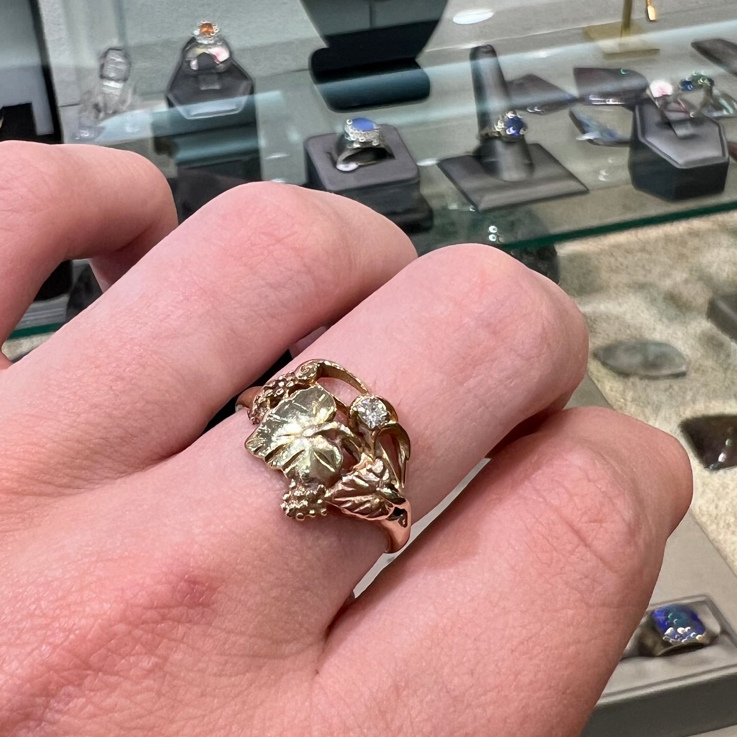 A ladies' two tone rose and yellow gold Black Hills gold diamond ring.  The ring exhibits a leaf design.