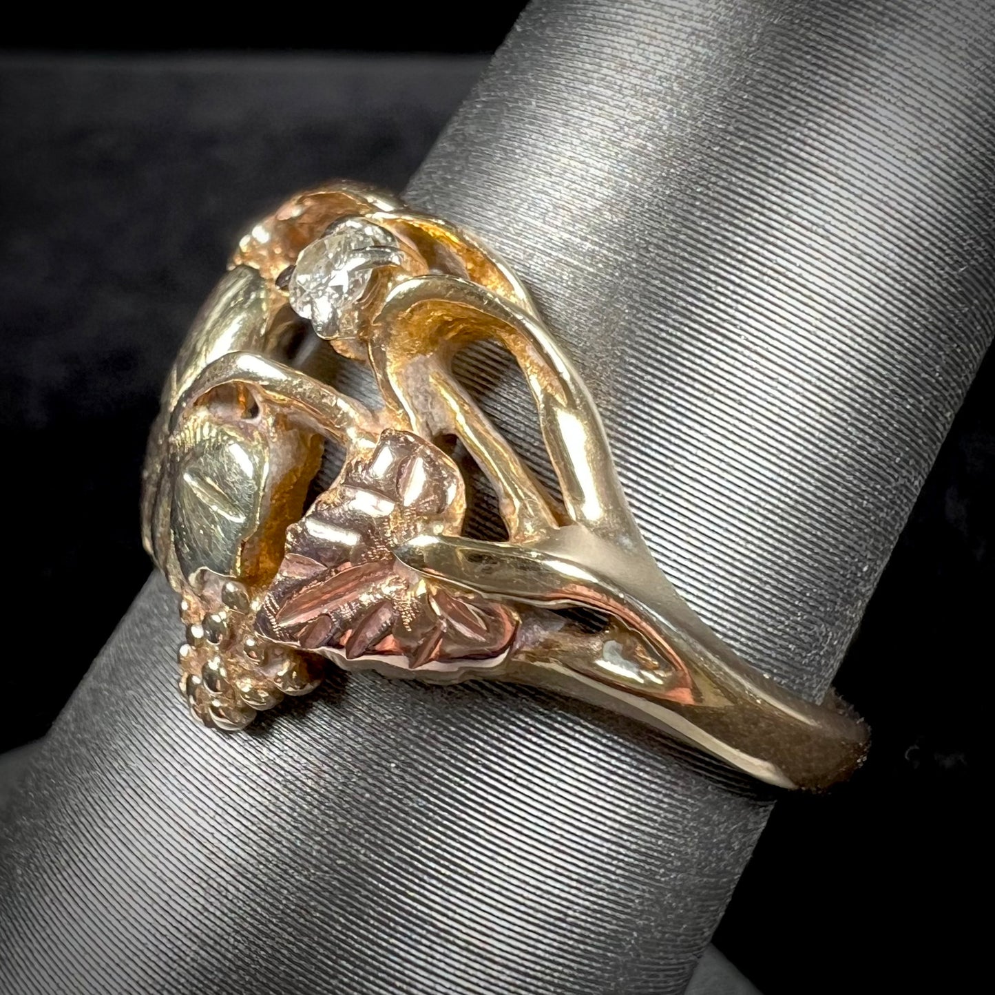 A ladies' two tone rose and yellow gold Black Hills gold diamond ring.  The ring exhibits a leaf design.