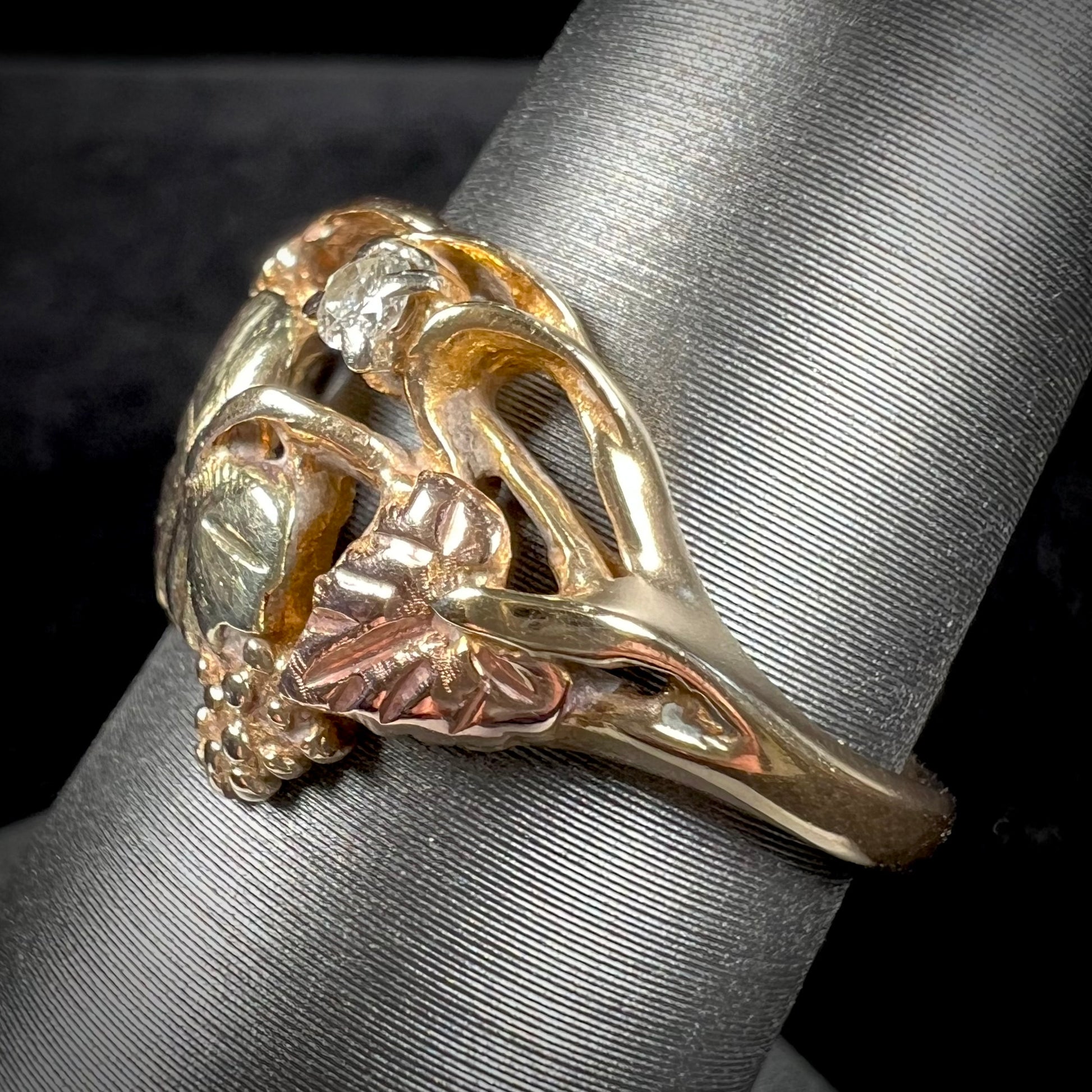 A ladies' two tone rose and yellow gold Black Hills gold diamond ring.  The ring exhibits a leaf design.