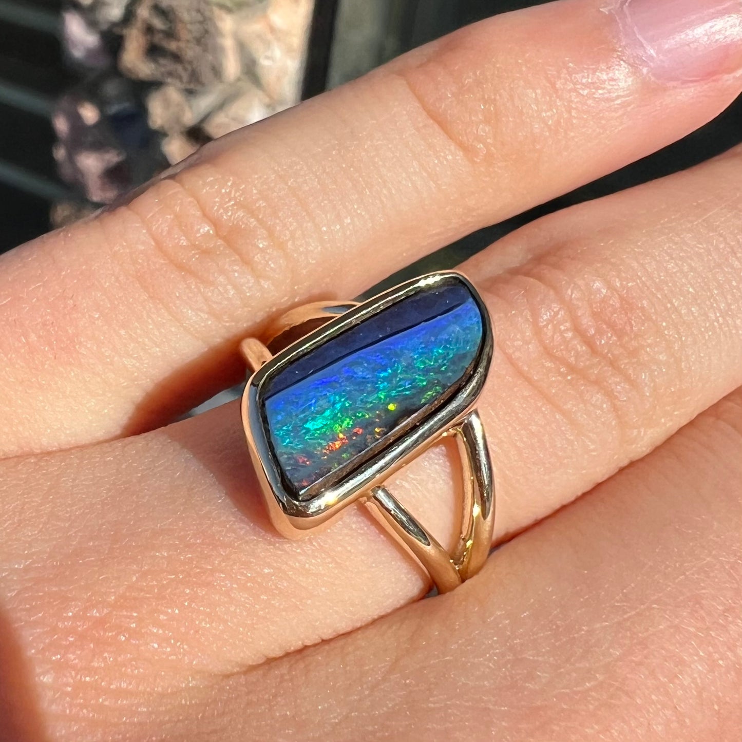 A ladies' split shank gold ring bezel set with a natural, Australian black boulder opal.
