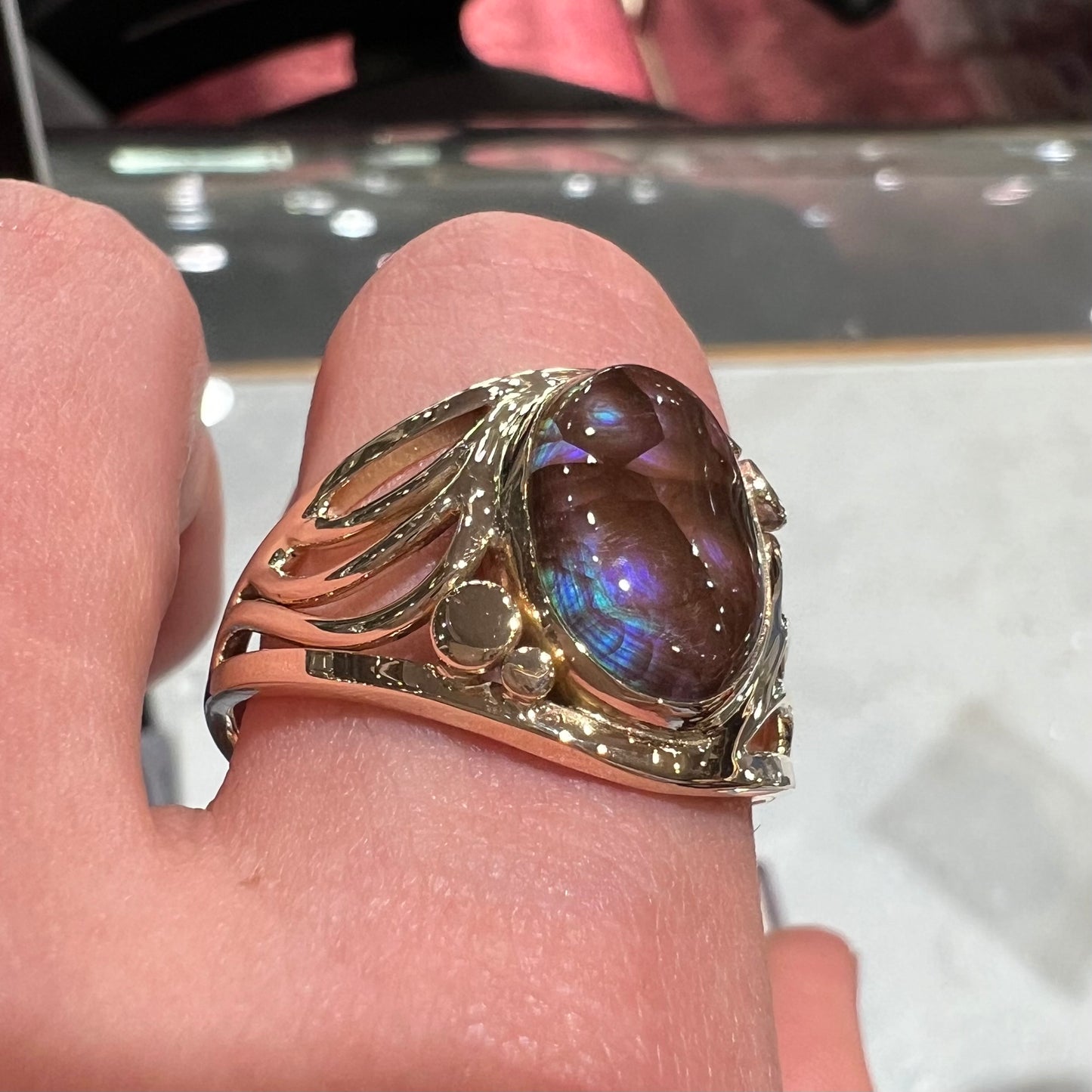 An oval cabochon cut fire agate with purple and blue colors set in a yellow gold men's ring.