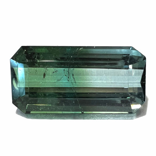 A loose, emerald cut bicolor tourmaline stone.  The colors blend from green to blue-green to sttel blue.