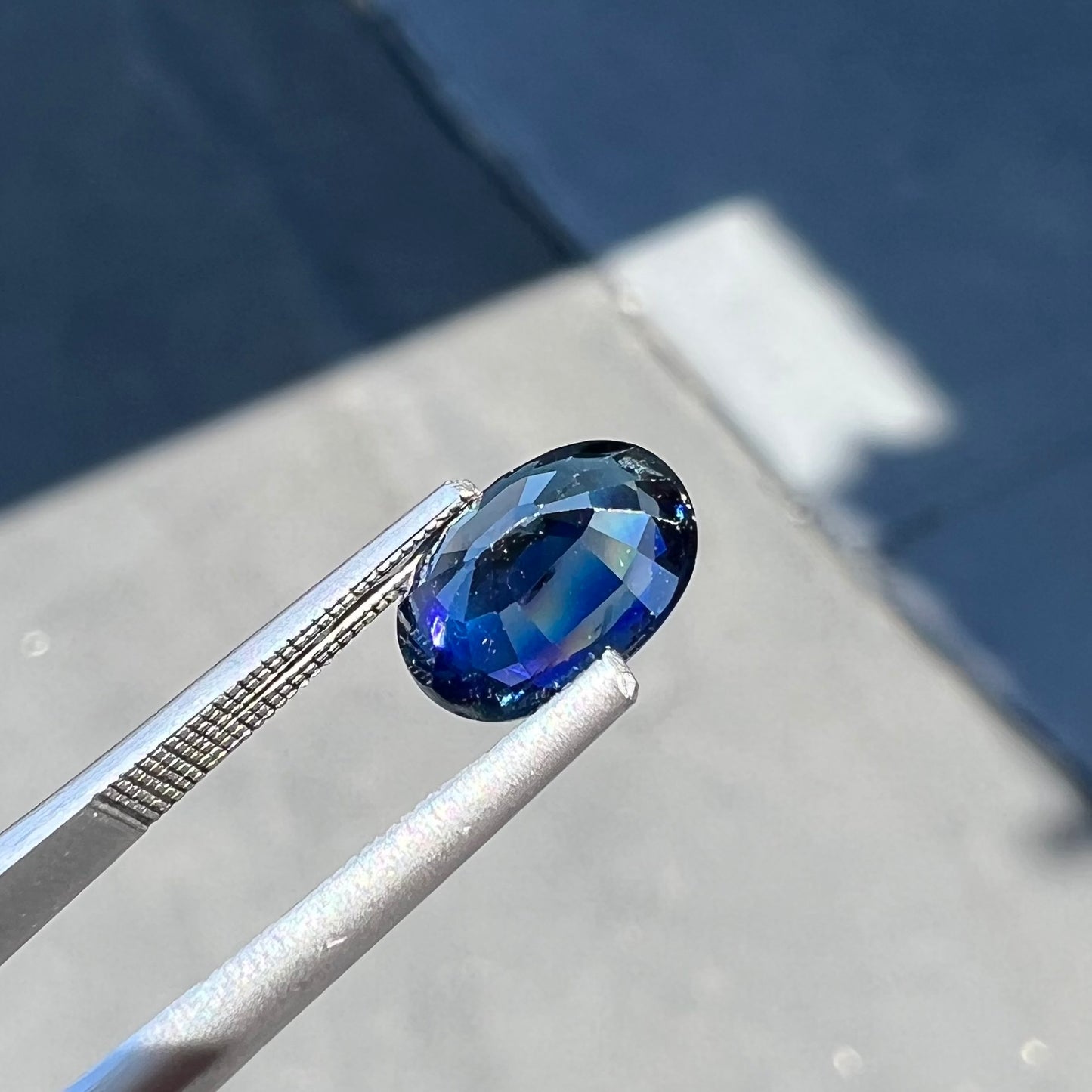 A loose, faceted oval cut natural blue sapphire gemstone.