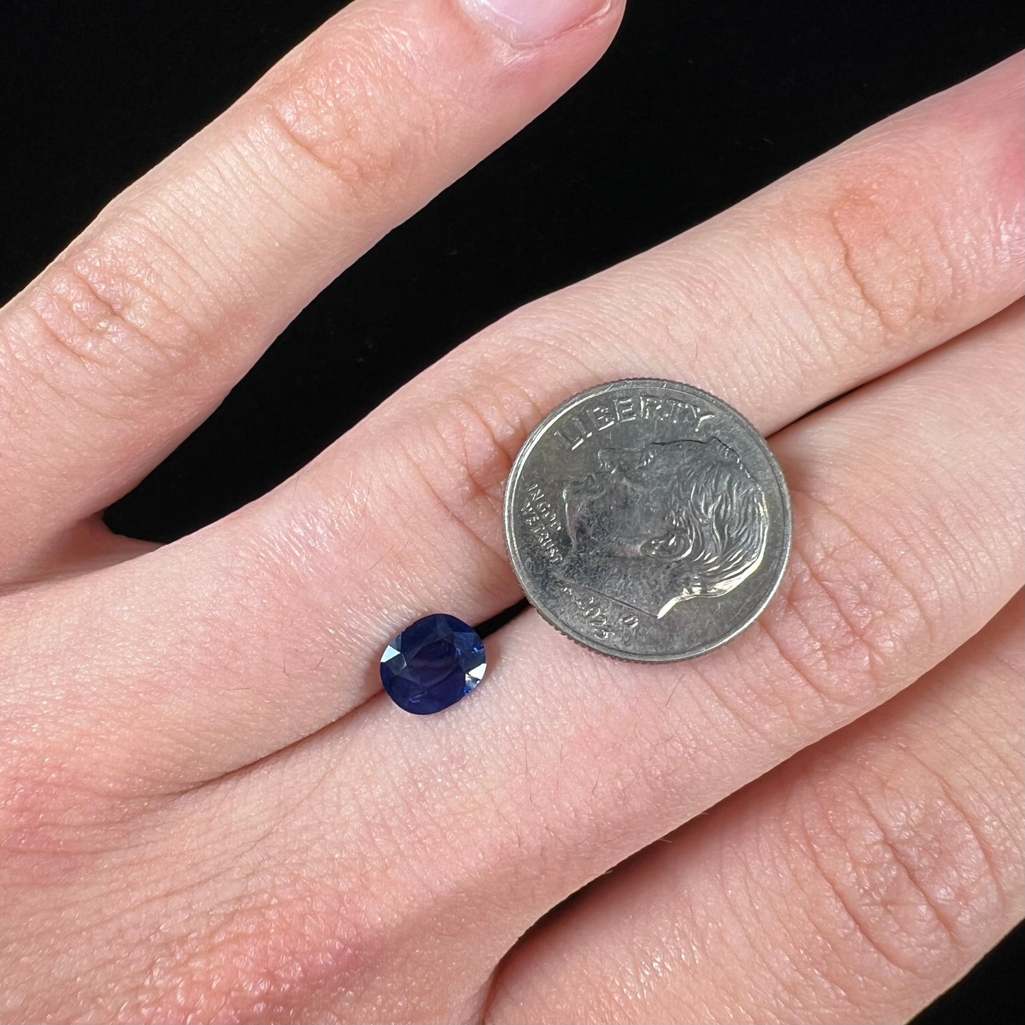A loose, faceted oval cut dark blue natural sapphire stone.