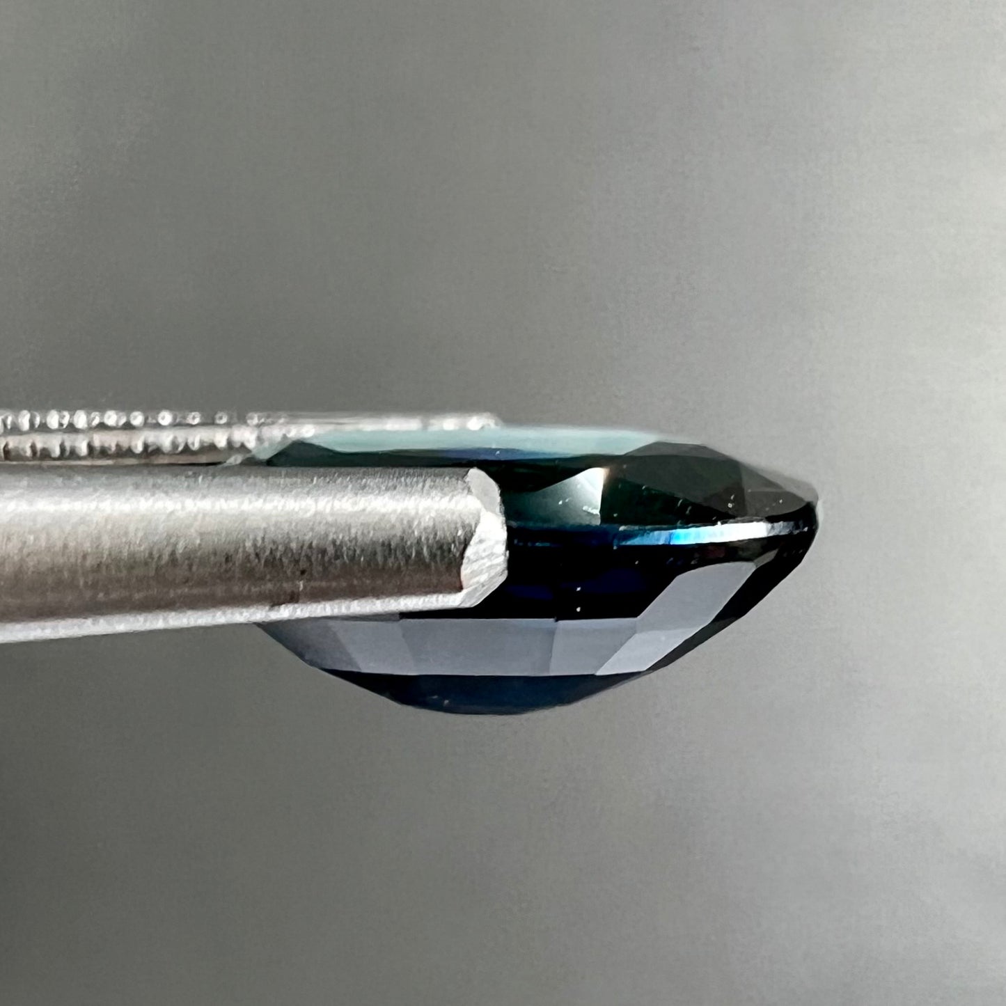 A loose, faceted oval cut natural blue sapphire gemstone.