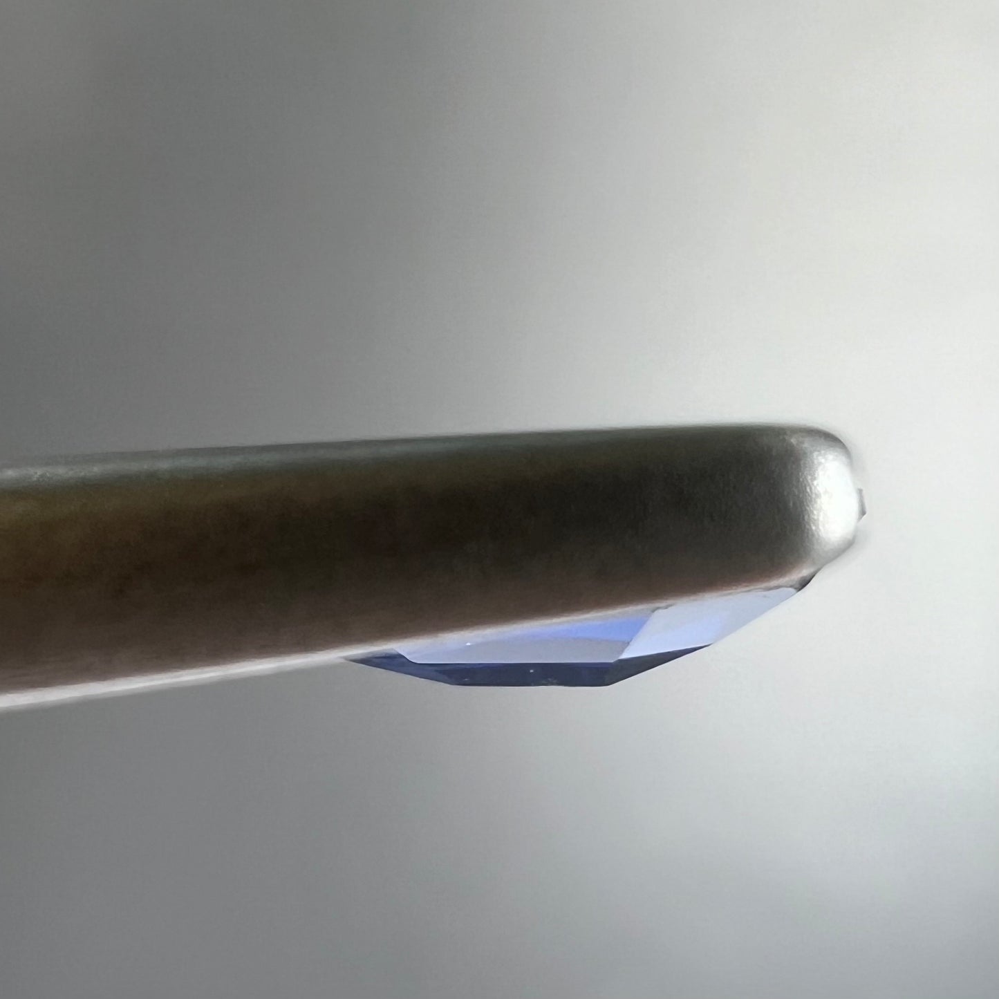 A loose, faceted oval cut dark blue natural sapphire stone.
