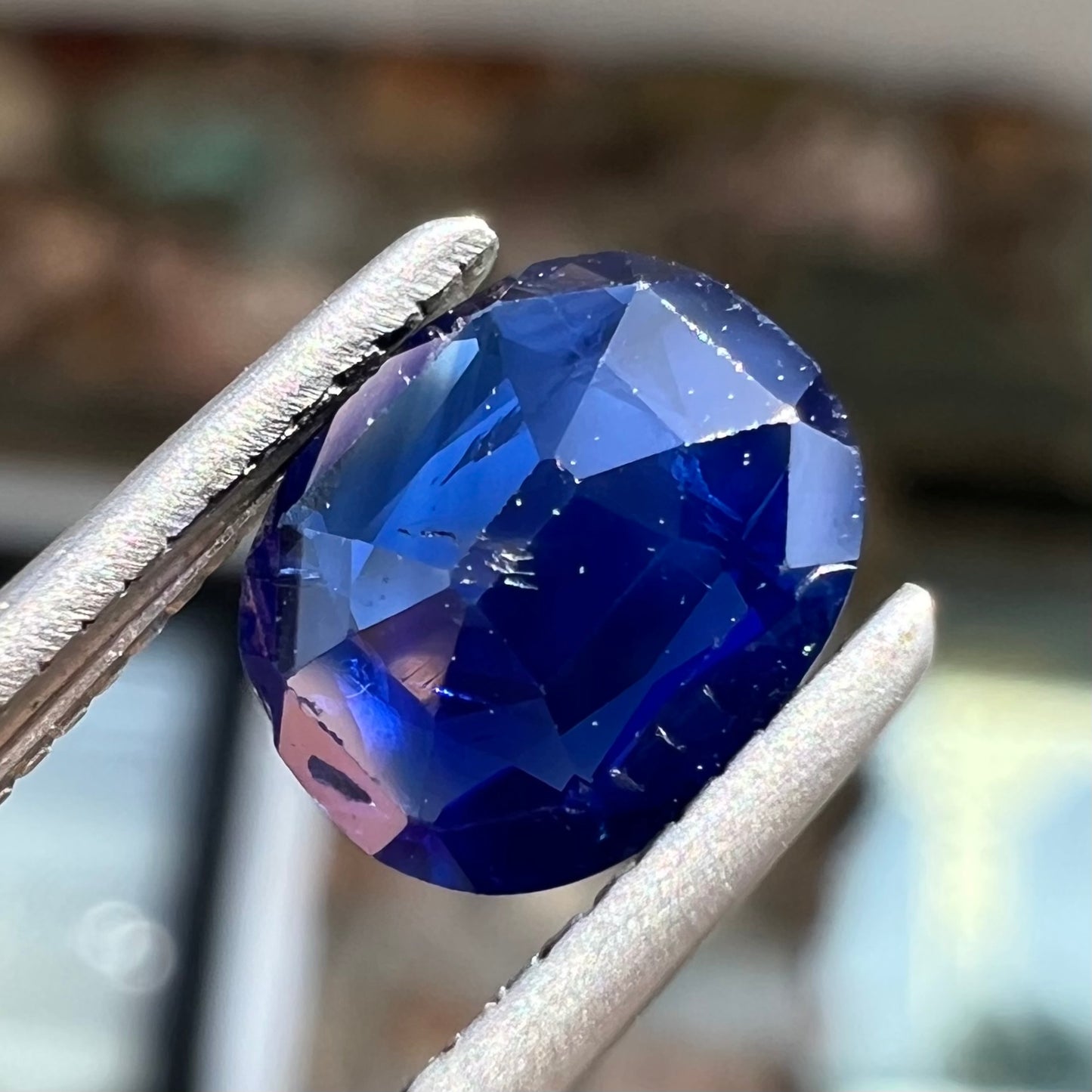 A loose, faceted oval cut dark blue natural sapphire stone.