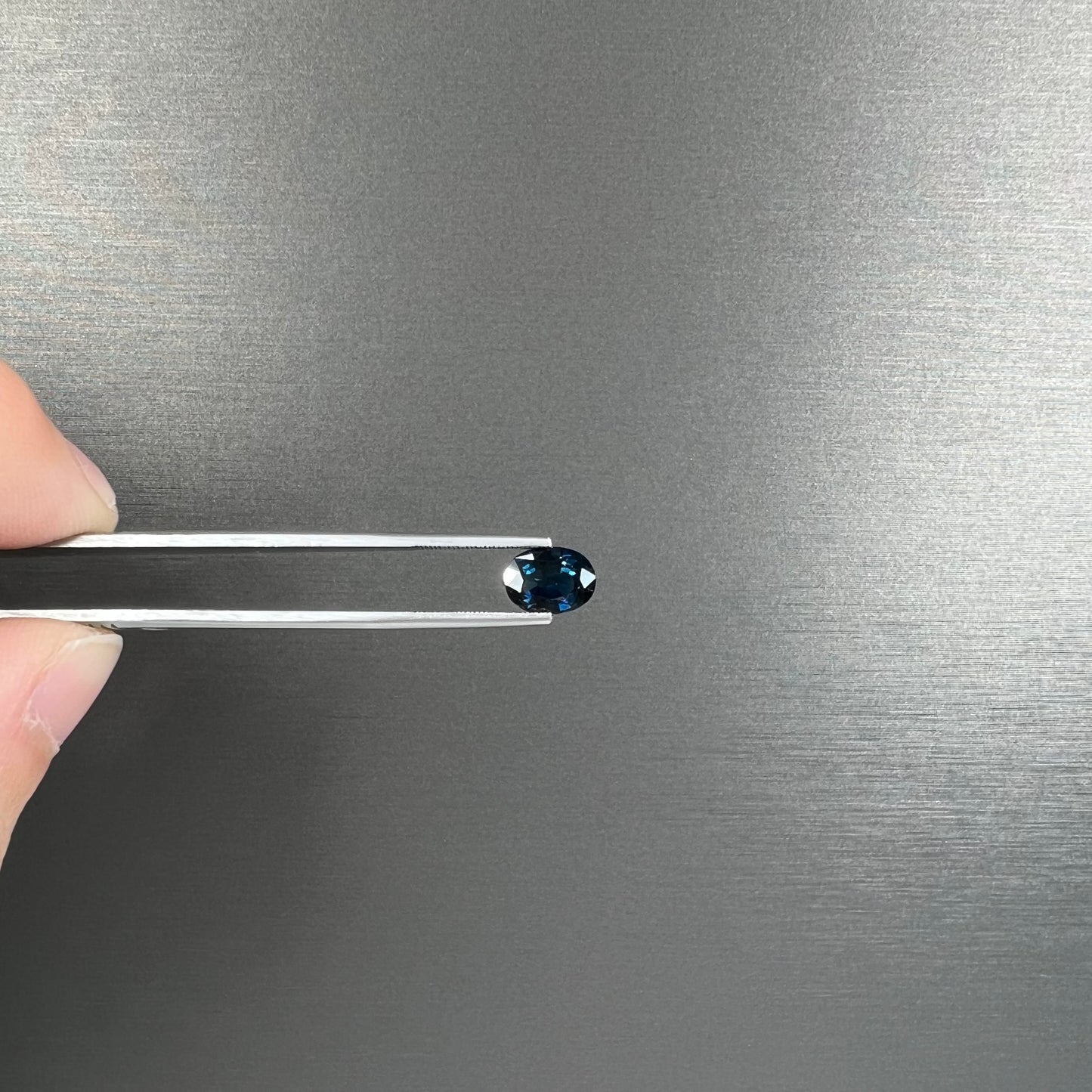 A loose, faceted oval cut natural blue sapphire gemstone.