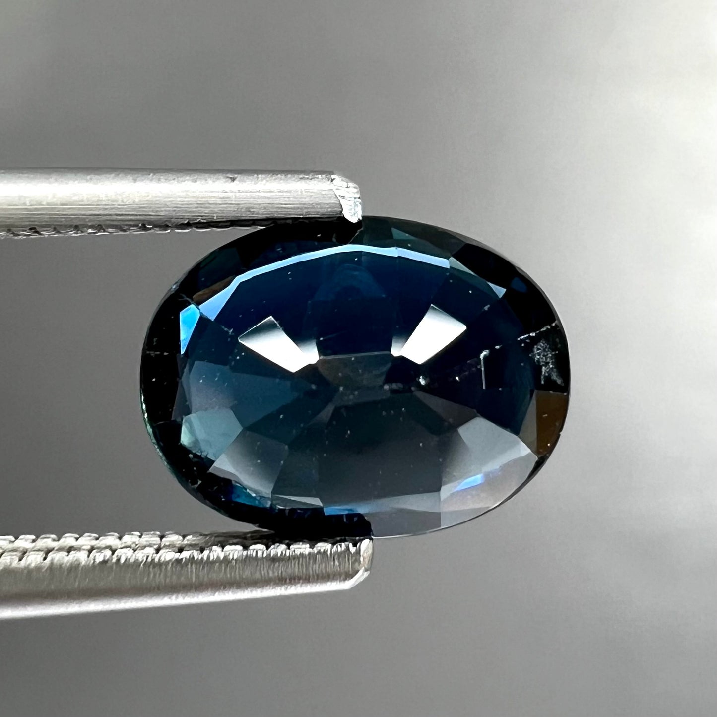 A loose, faceted oval cut natural blue sapphire gemstone.