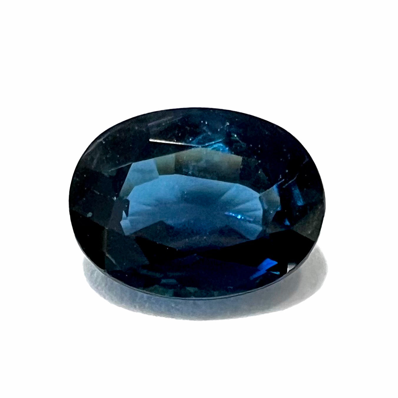 A loose, faceted oval cut natural blue sapphire gemstone.