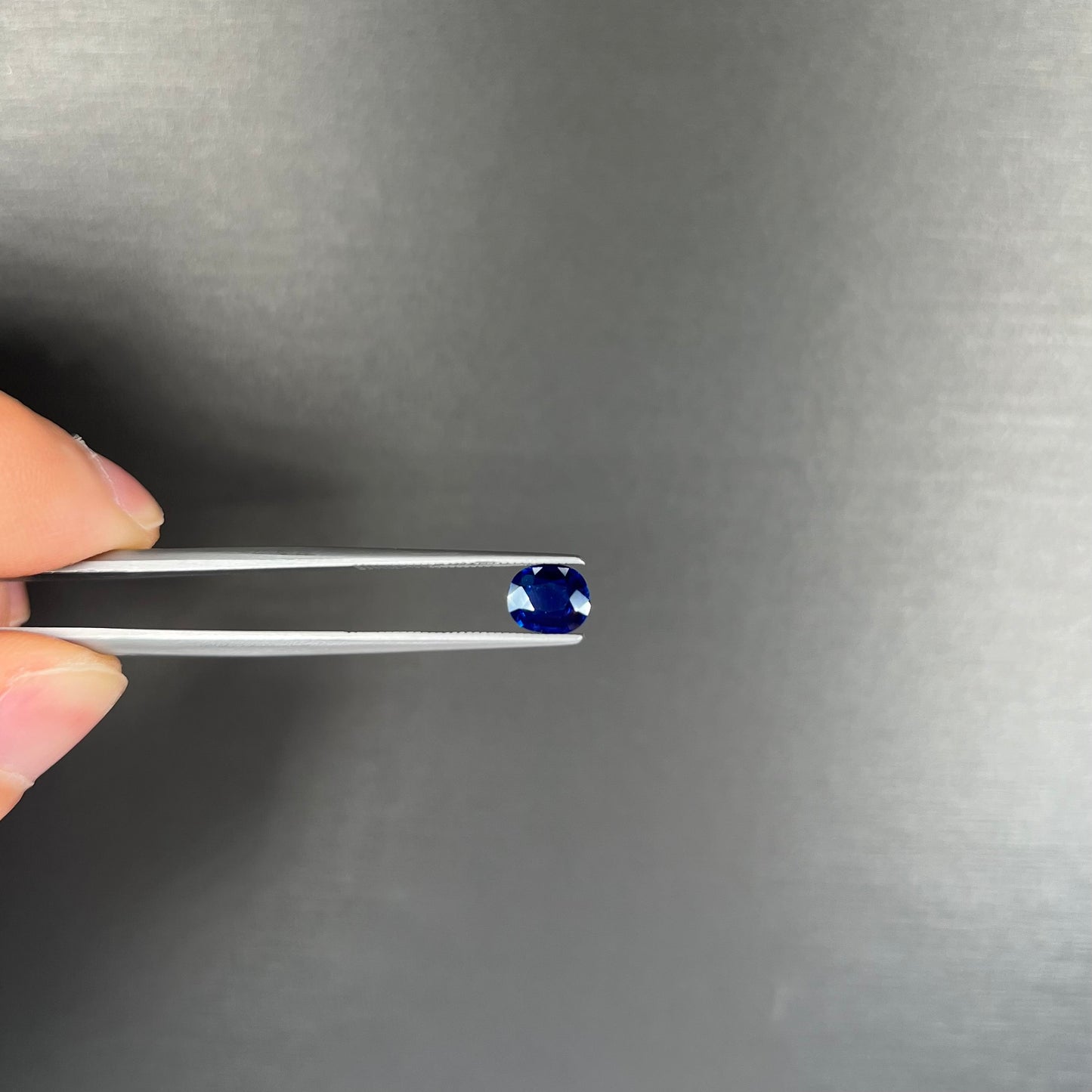A loose, faceted oval cut dark blue natural sapphire stone.