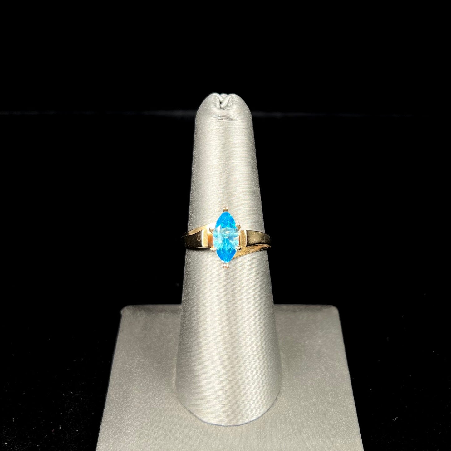 A ladies' estate yellow gold ring, prong set with a marquise cut blue topaz stone. There are scratches on the shank.
