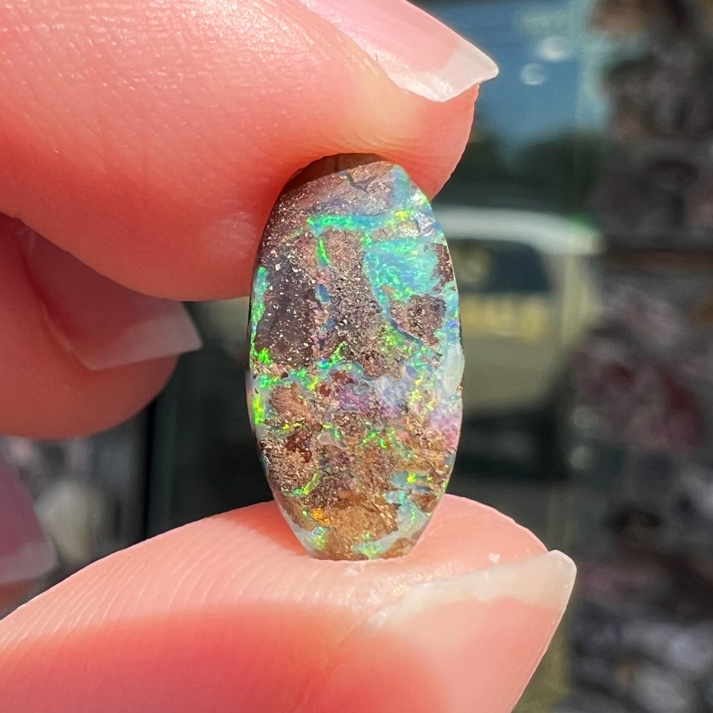 A loose, oval cabochon cut Koroit boulder opal stone. The opal has a bright green color.
