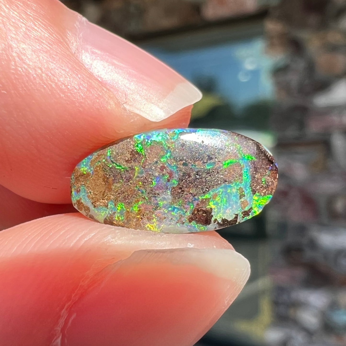 A loose, oval cabochon cut Koroit boulder opal stone. The opal has a bright green color.