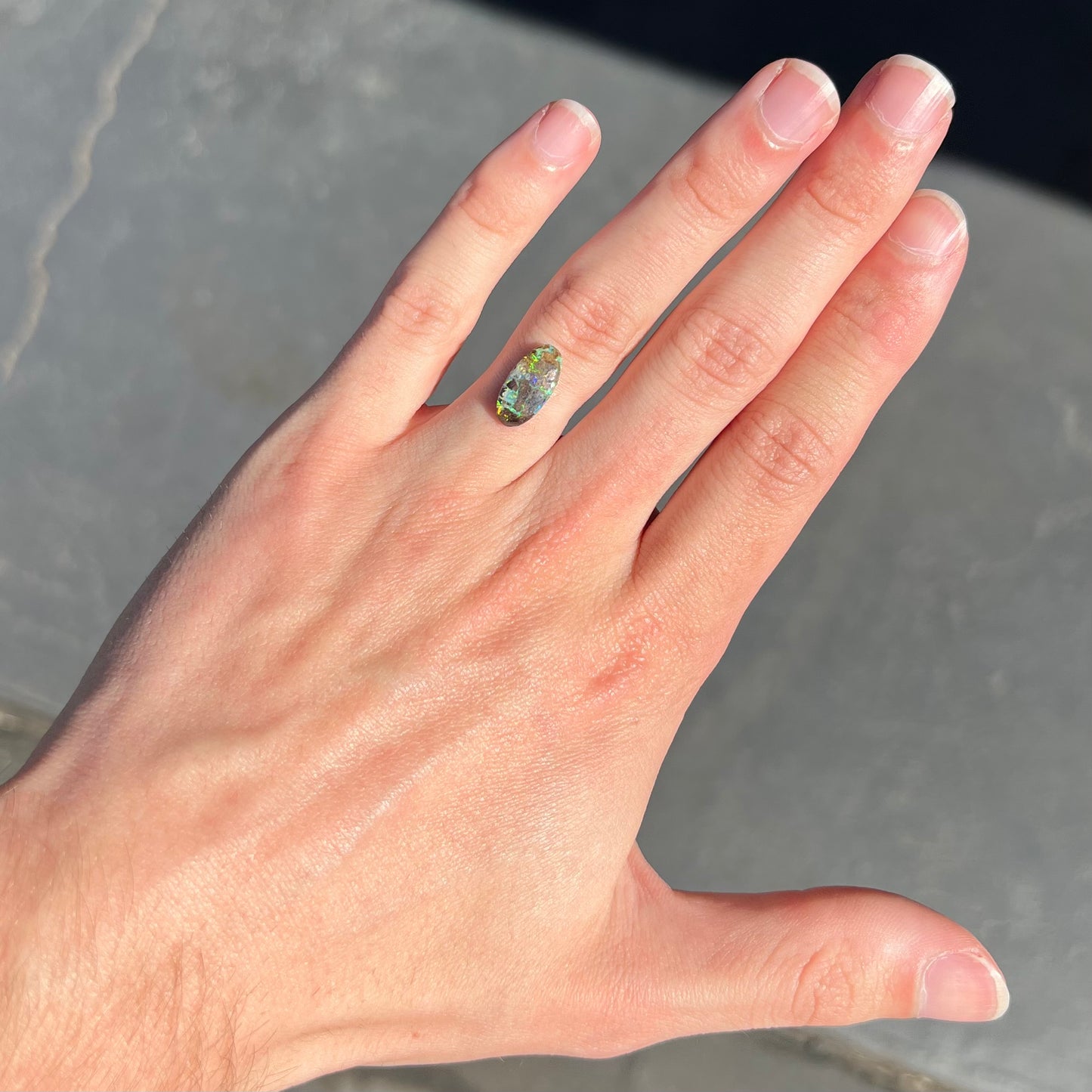 A loose, oval cabochon cut Koroit boulder opal stone. The opal has a bright green color.