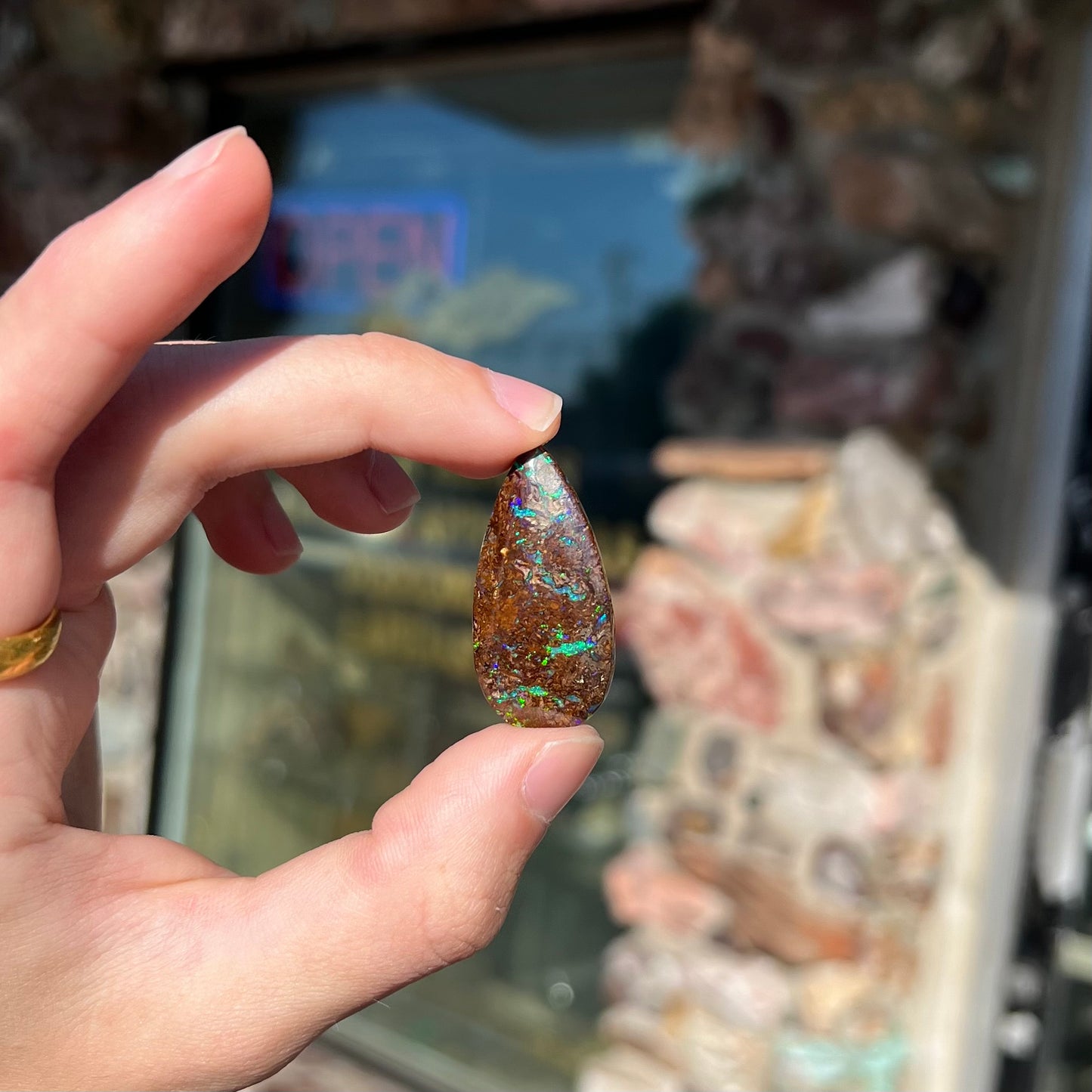 A pear shaped boulder opal stone from Koroit, Australia. The opal has blue and green flashes.