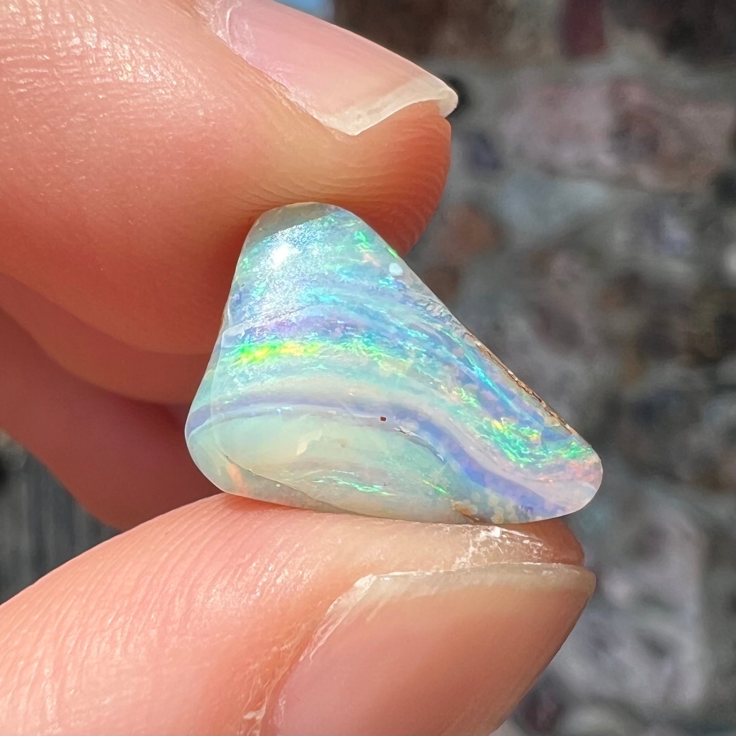 A loose, freeform boulder opal stone from Quilpie, Australia. The opal has a fissure inclusion.