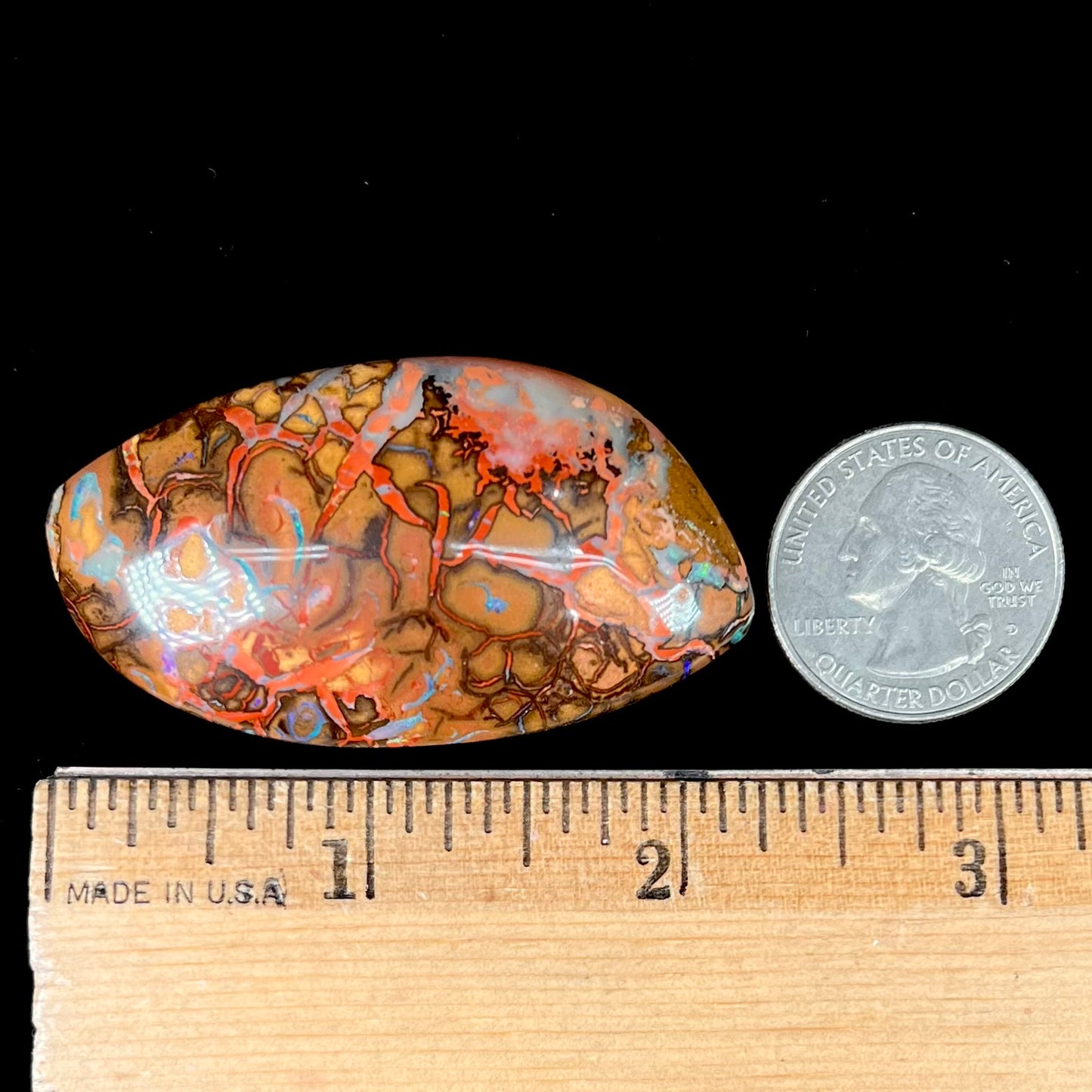 A polished boulder opal stone from Koroit, Australia. The stone has been drilled with a bead hole.