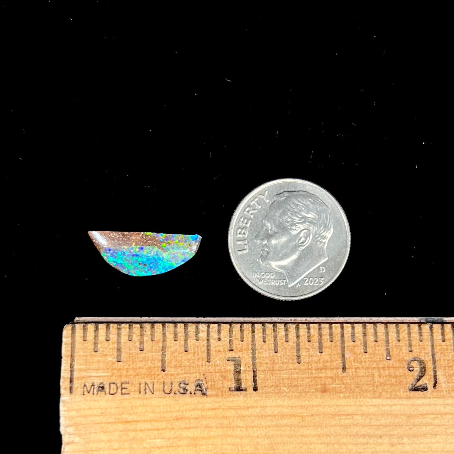 A freeform shaped boulder opal stone from Quilpie, Australia. The opal has bright blue and green play of color.