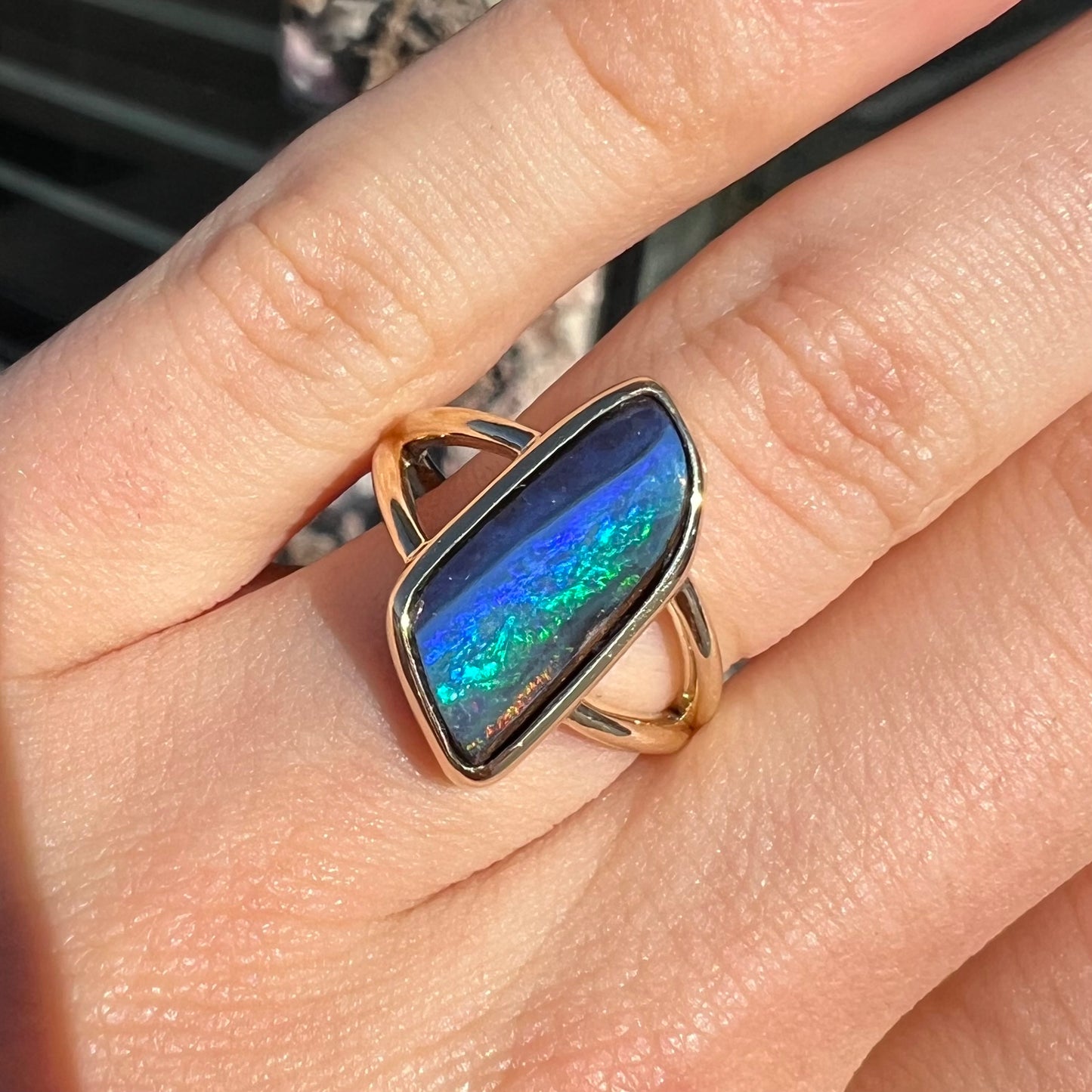 A ladies' split shank gold ring bezel set with a natural, Australian black boulder opal.