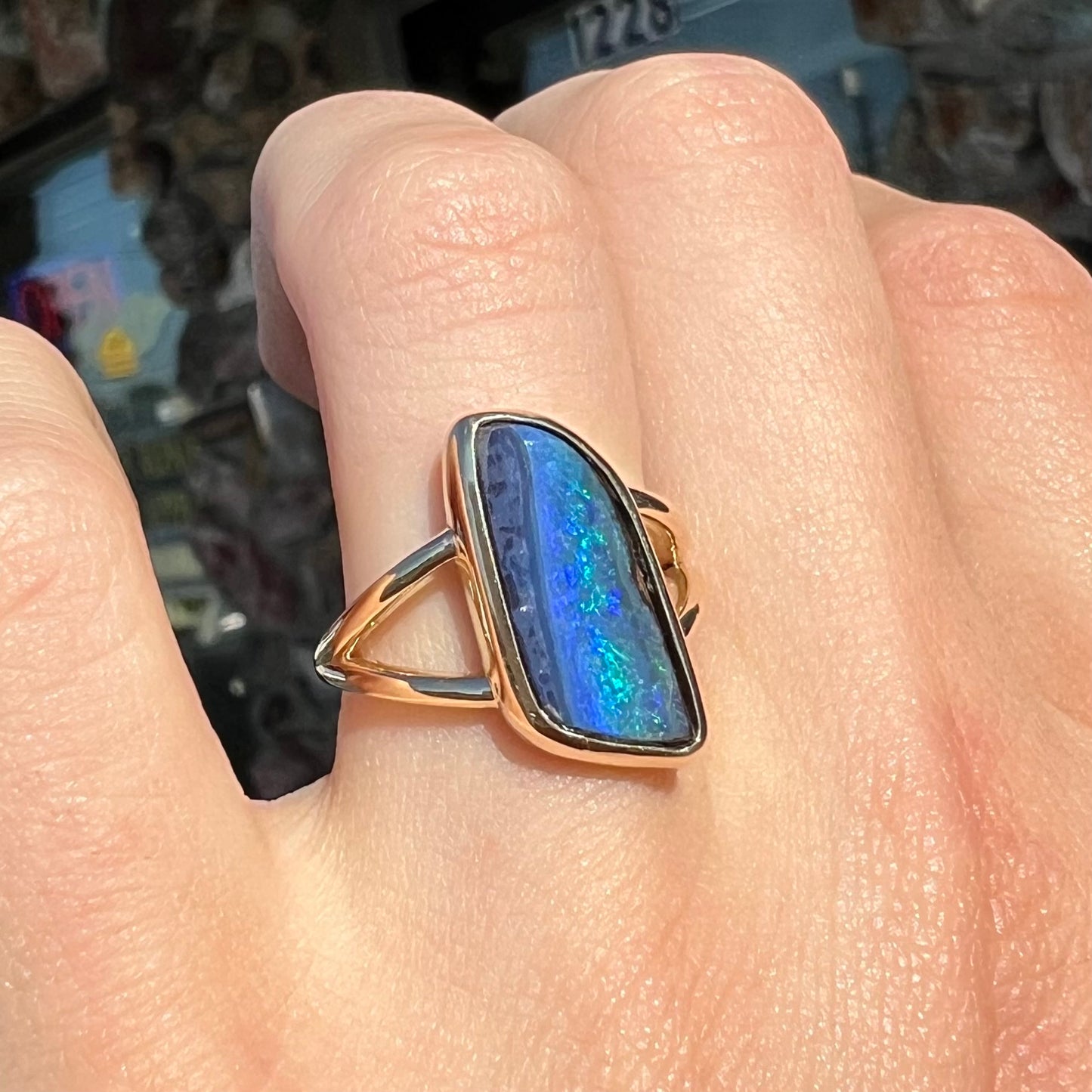 A ladies' split shank gold ring bezel set with a natural, Australian black boulder opal.