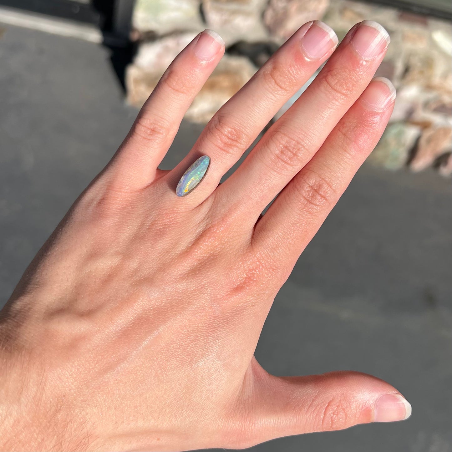 A loose, marquise cut boulder opal from Quilpie, Australia. The opal has green and red wave patterns.