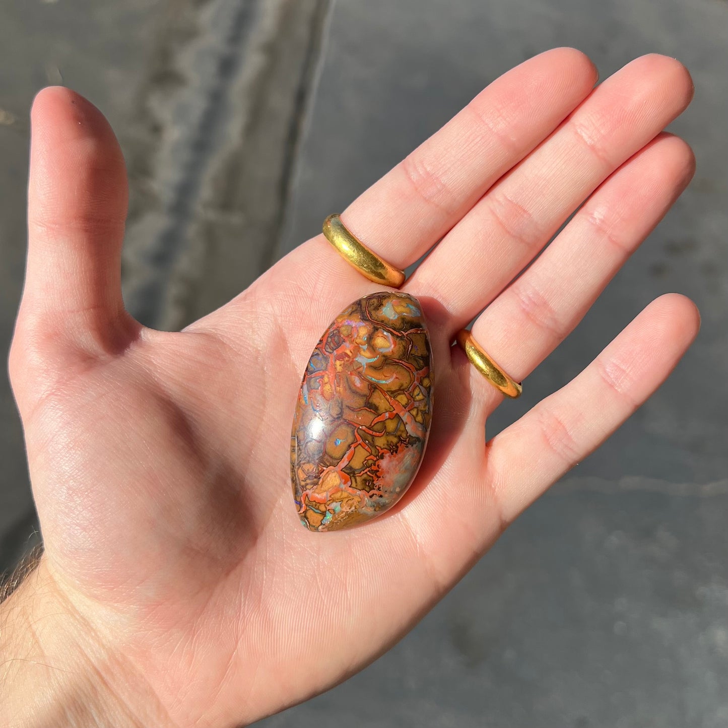 A polished boulder opal stone from Koroit, Australia. The stone has been drilled with a bead hole.