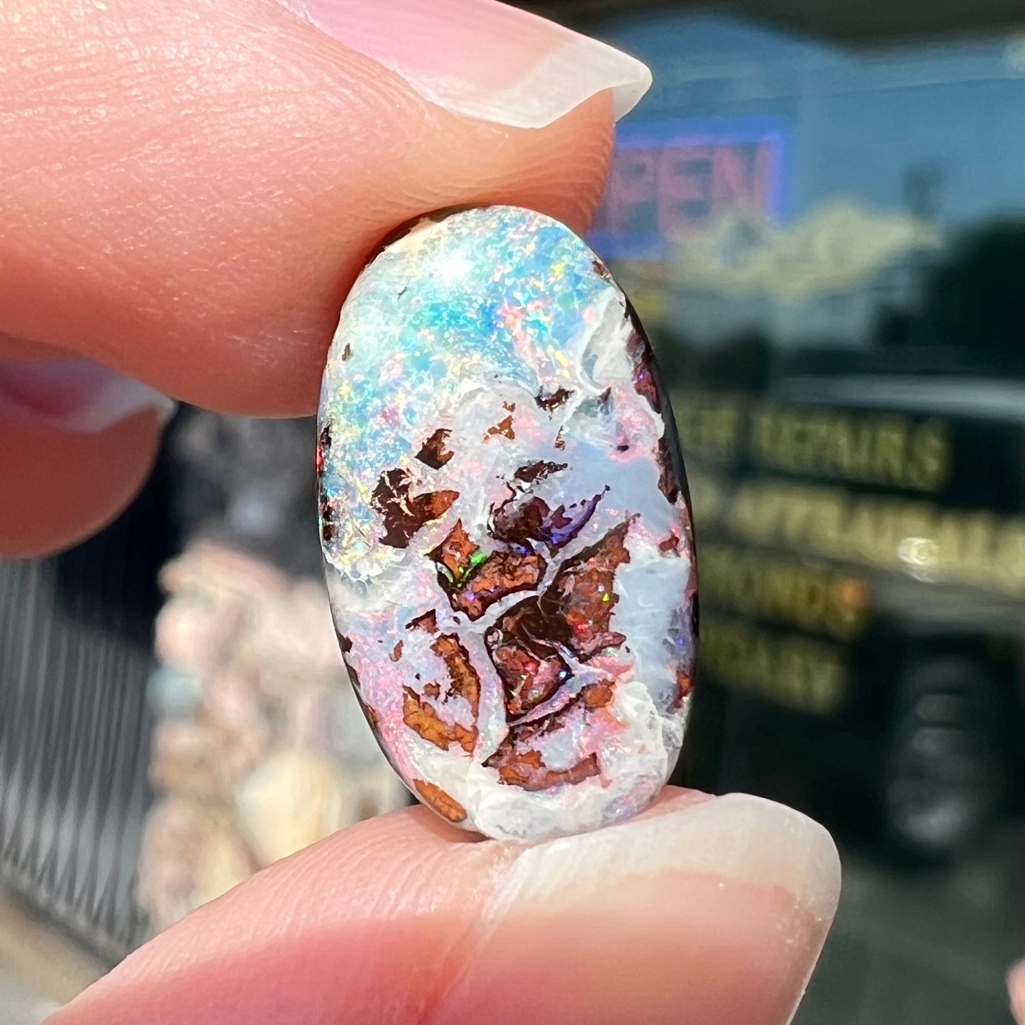 An oval cabochon cut boulder opal stone from Koroit, Australia. The opal has a white body tone.