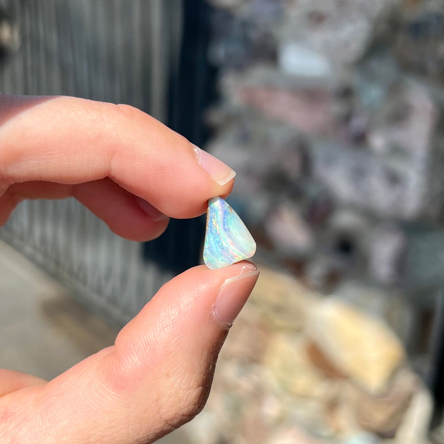 A loose, freeform boulder opal stone from Quilpie, Australia. The opal has a fissure inclusion.