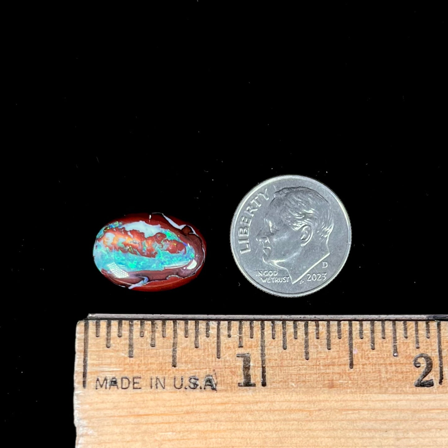 A loose, oval cabochon cut boulder opal stone from Australia. The opal has blue and green veins in an ironstone matrix.