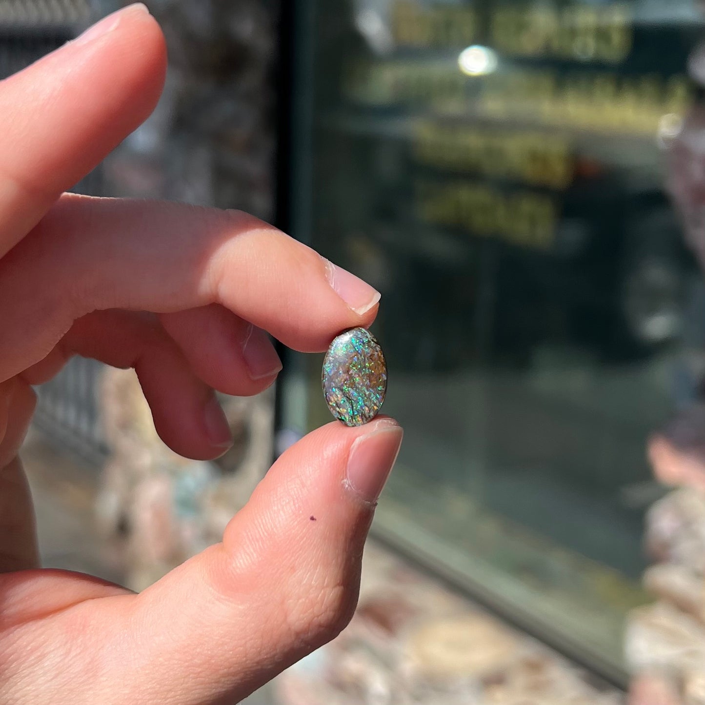 A loose, oval cabochon cut matrix boulder opal stone from Koroit, Australia. The opal shines with green and blue colors.