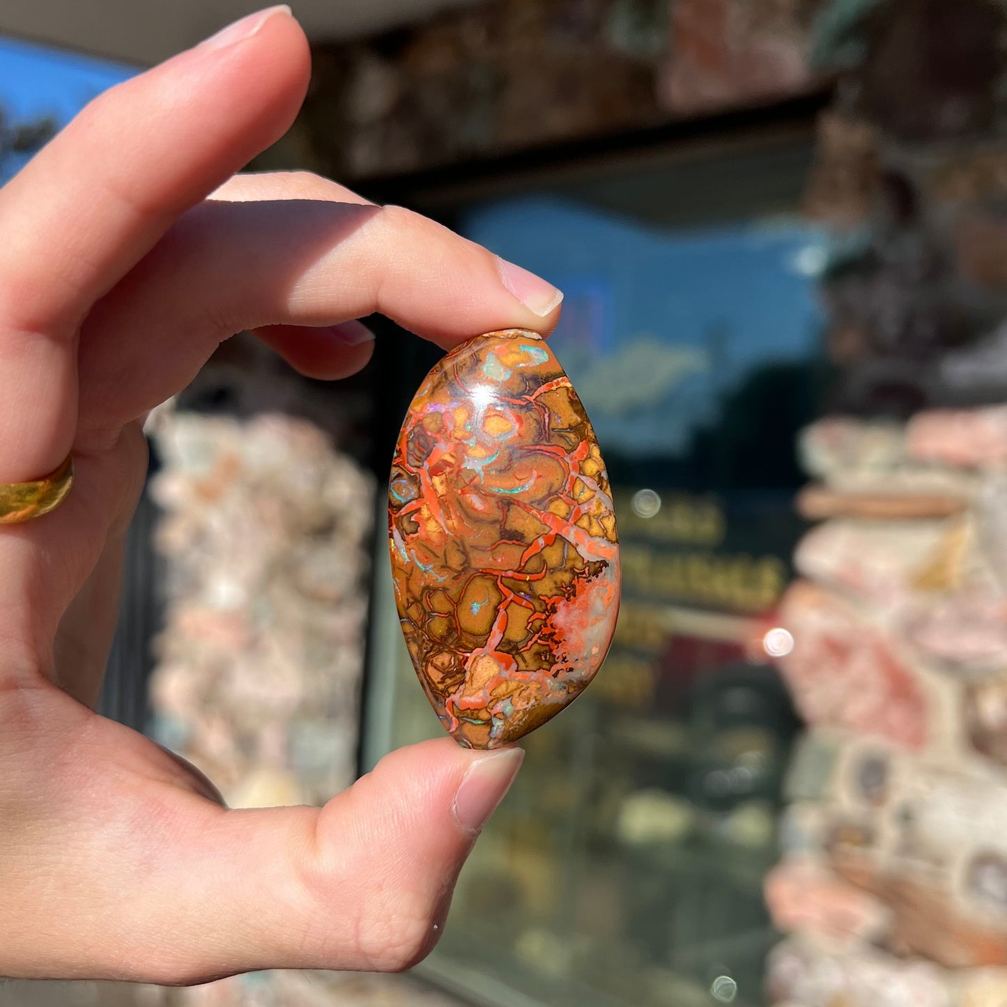 A polished boulder opal stone from Koroit, Australia. The stone has been drilled with a bead hole.