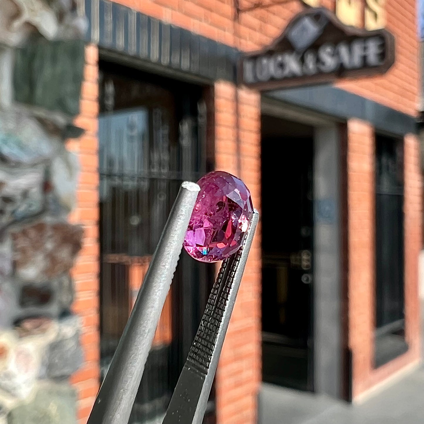 A loose, faceted oval cut natural purple sapphire. The stone has a burst crystal inclusion.