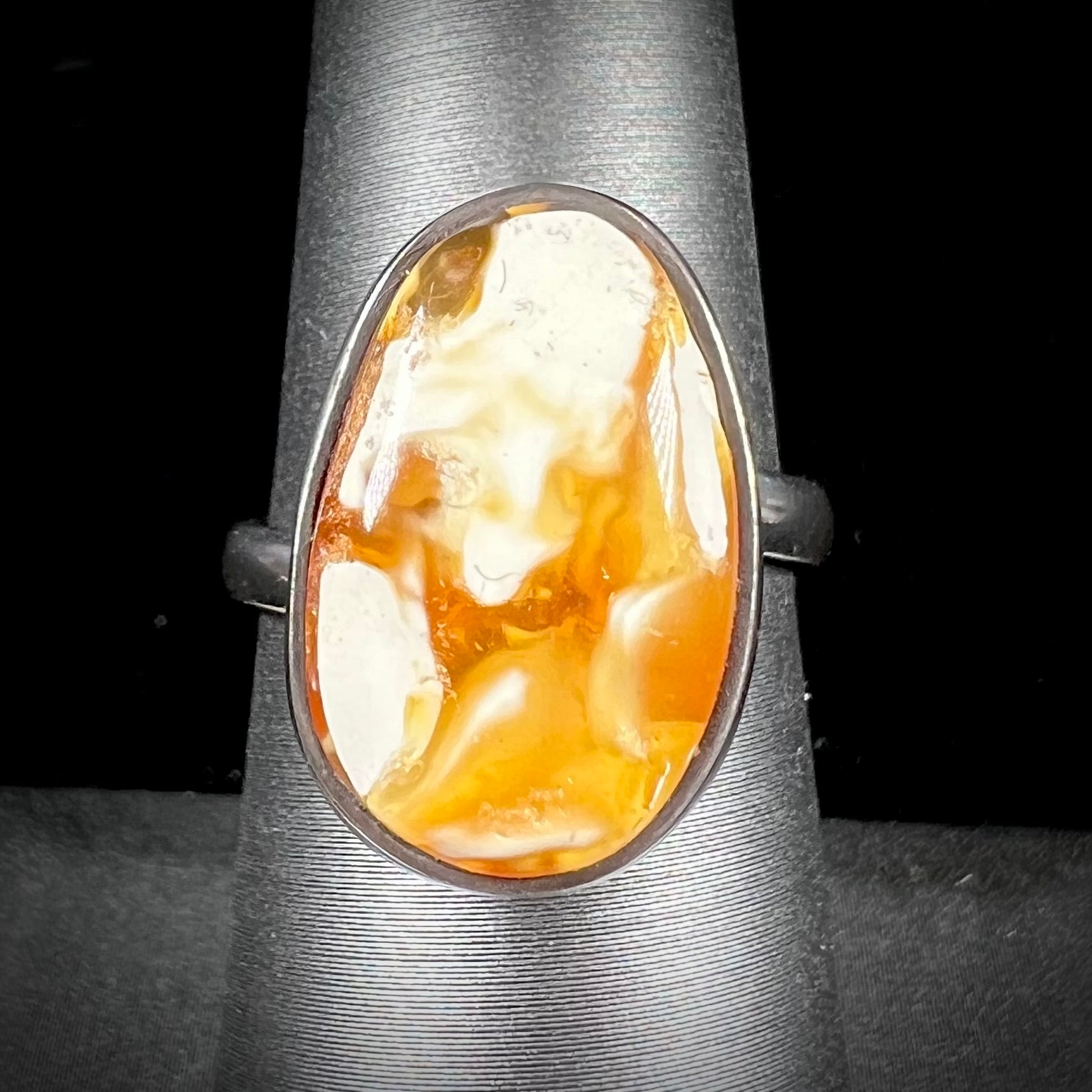 An adjustable sterling silver solitaire ring set with a cabochon cut butterscotch amber stone.