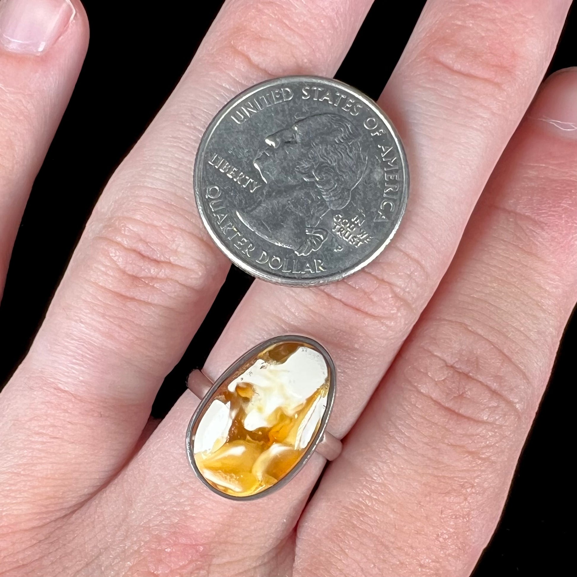 An adjustable sterling silver solitaire ring set with a cabochon cut butterscotch amber stone.
