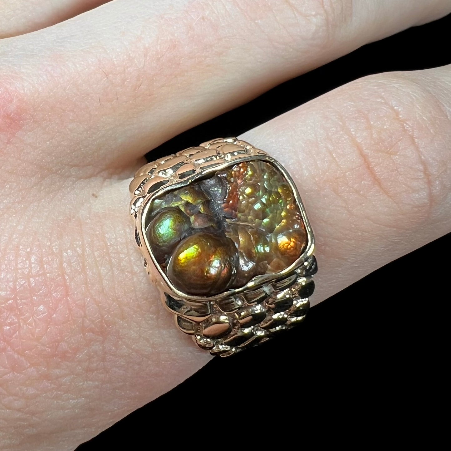 A men's yellow gold, nugget style ring set with a bubbly, California fire agate stone.