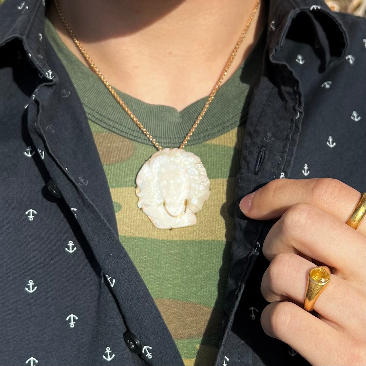 A cameo necklace carved by white crystal opal and held with gold prongs. The cameo is wearing a gold chain.