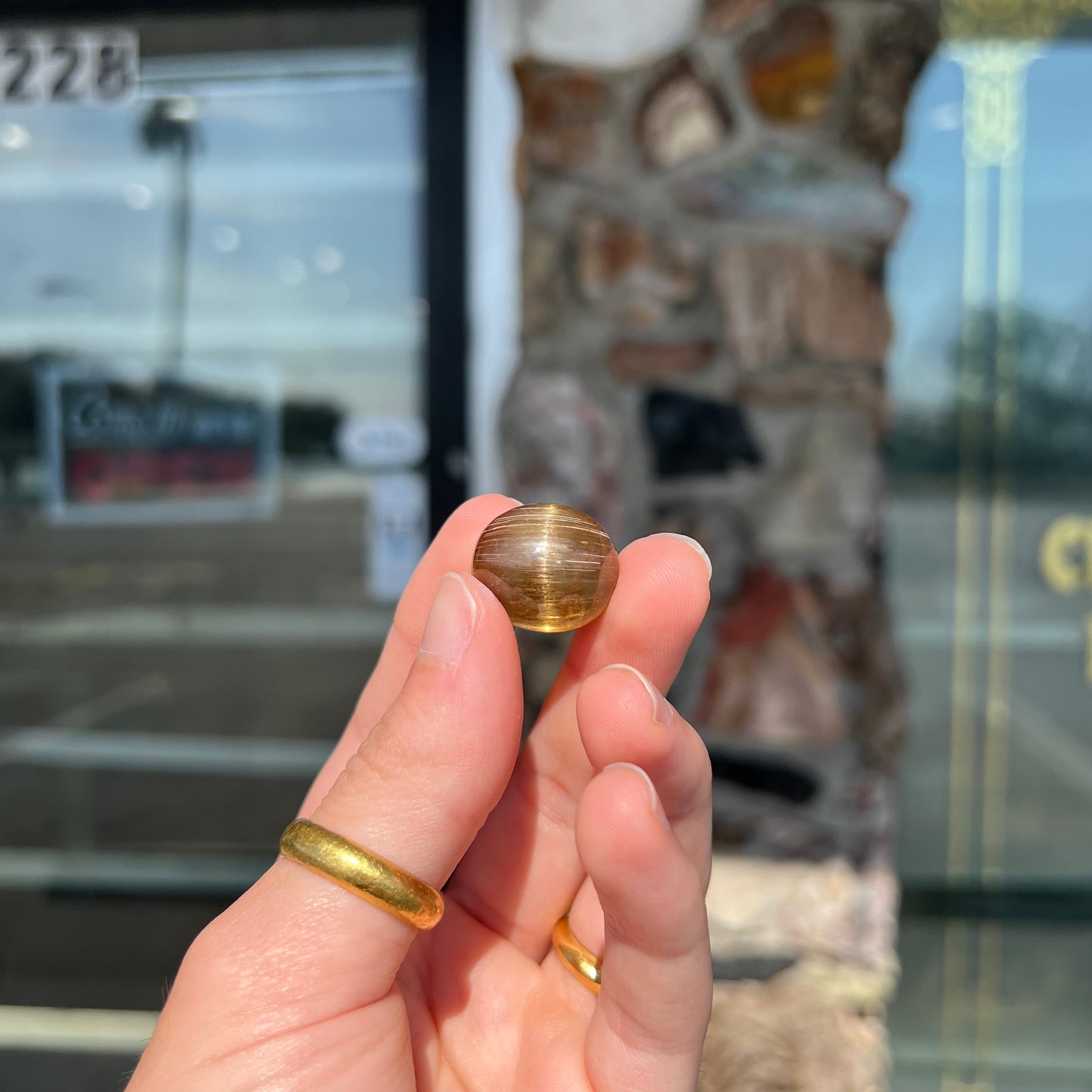 A loose, golden brown cat's eye dravite tourmaline gemstone. The stone is cut into an oval shaped cabochon.