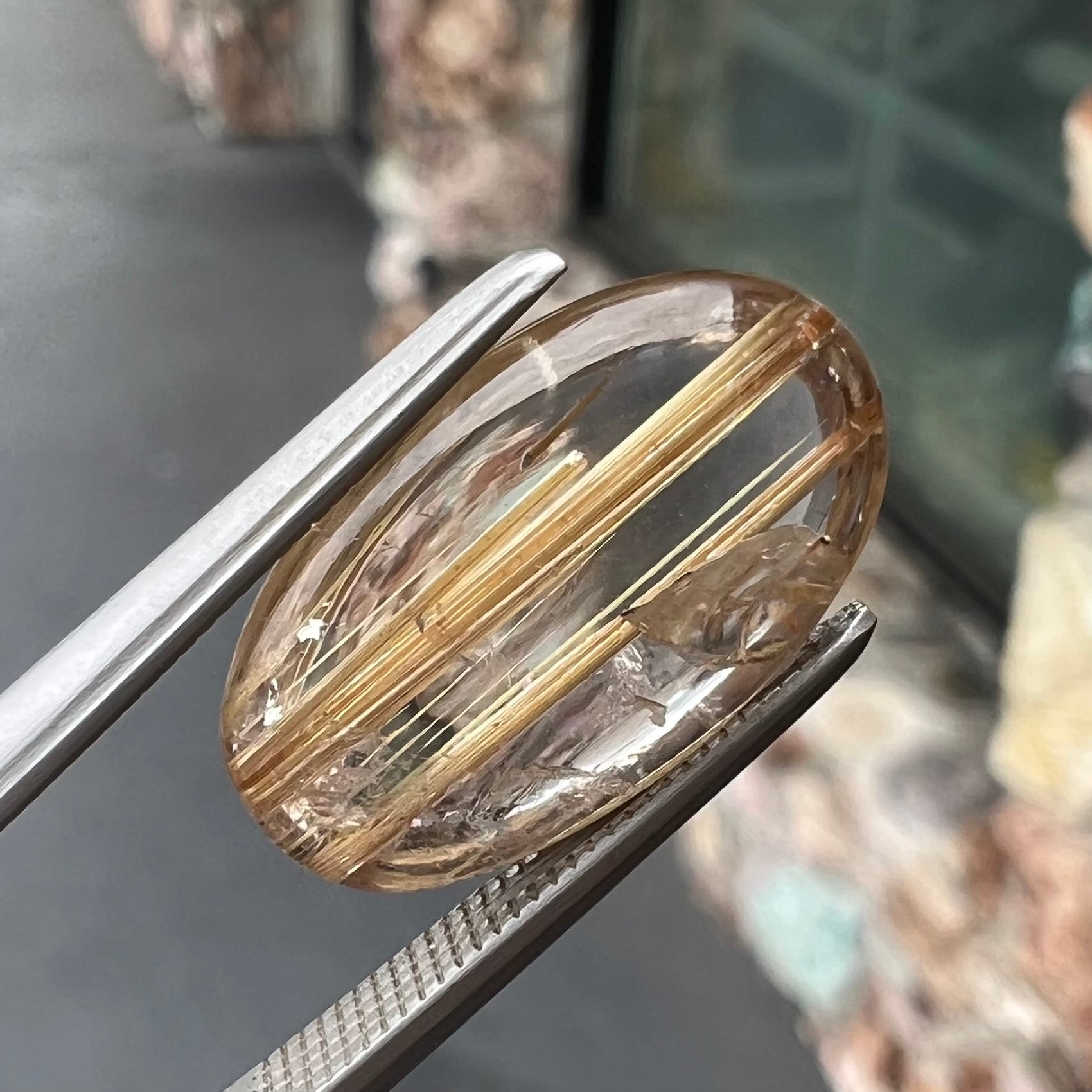 A loose, oval cabochon cut cat's eye golden rutilated quartz stone.