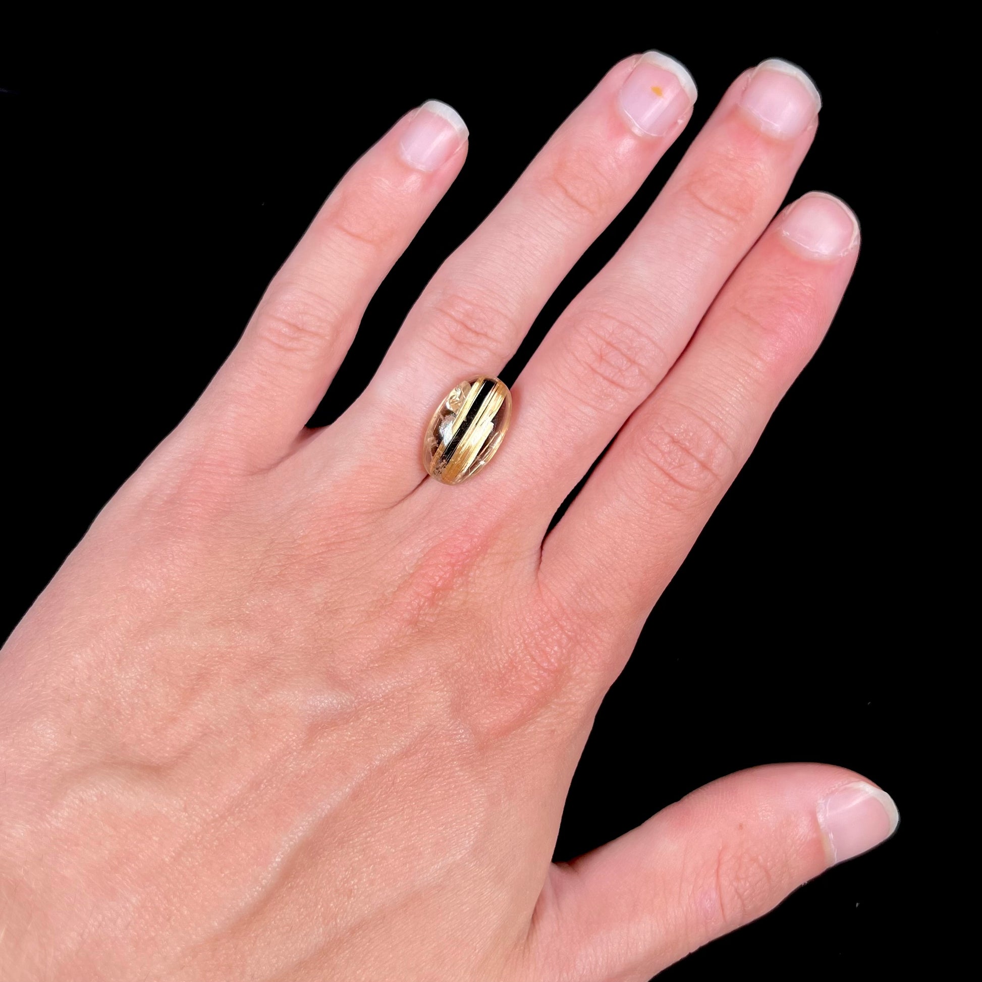 A loose, oval cabochon cut cat's eye golden rutilated quartz stone.