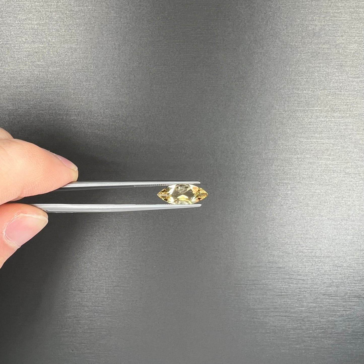 A loose, marquise cut golden beryl gemstone. The stone is a light yellow color.