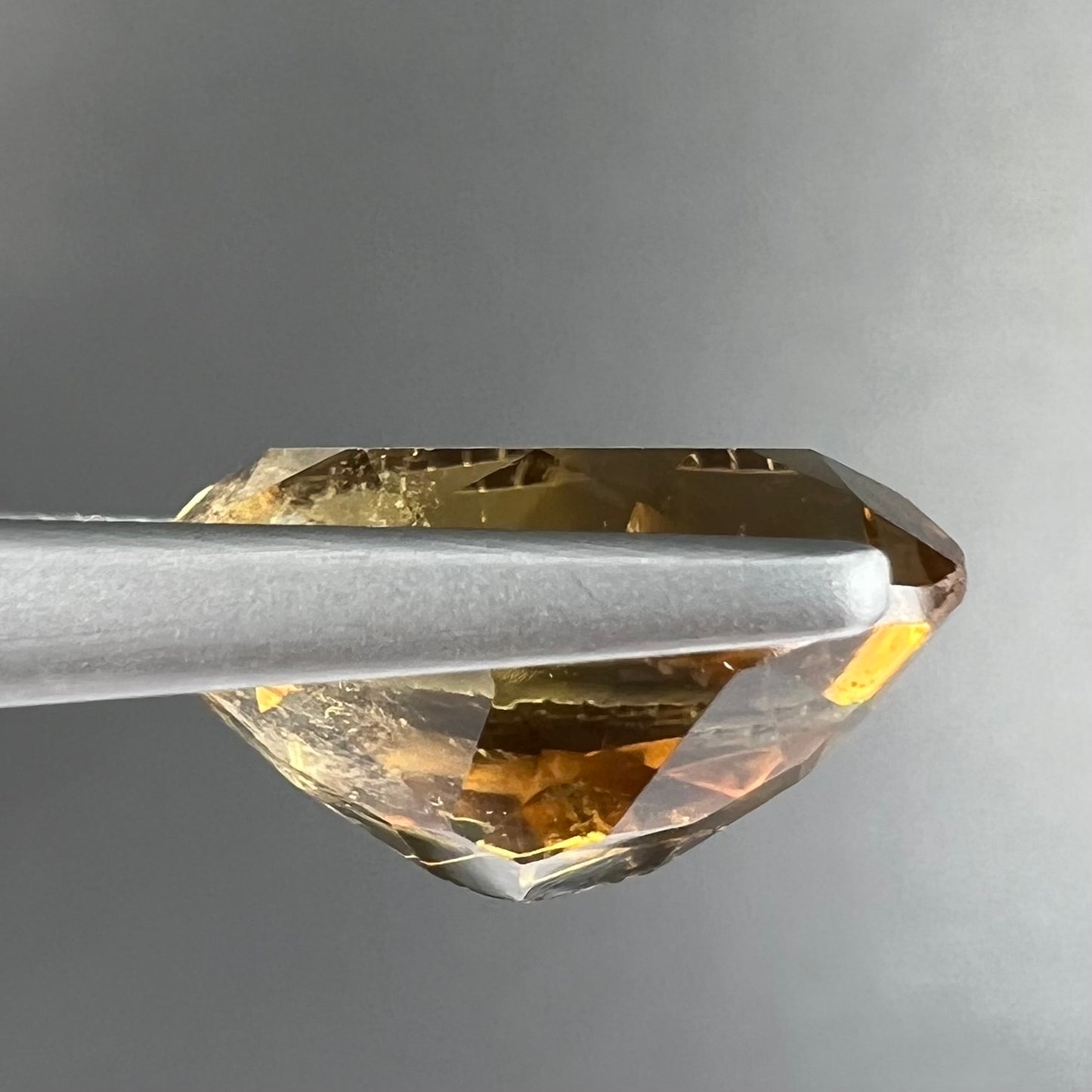 A loose, oval cut citrine gemstone. The stone is heavily included and roughly cut.