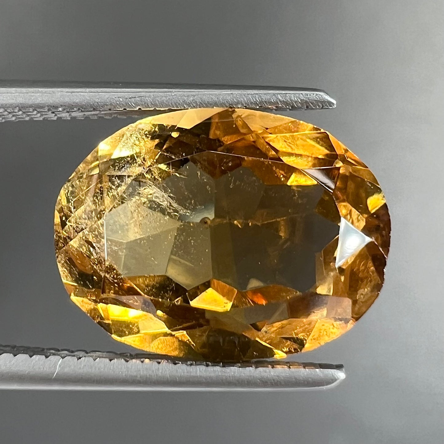 A loose, oval cut citrine gemstone. The stone is heavily included and roughly cut.