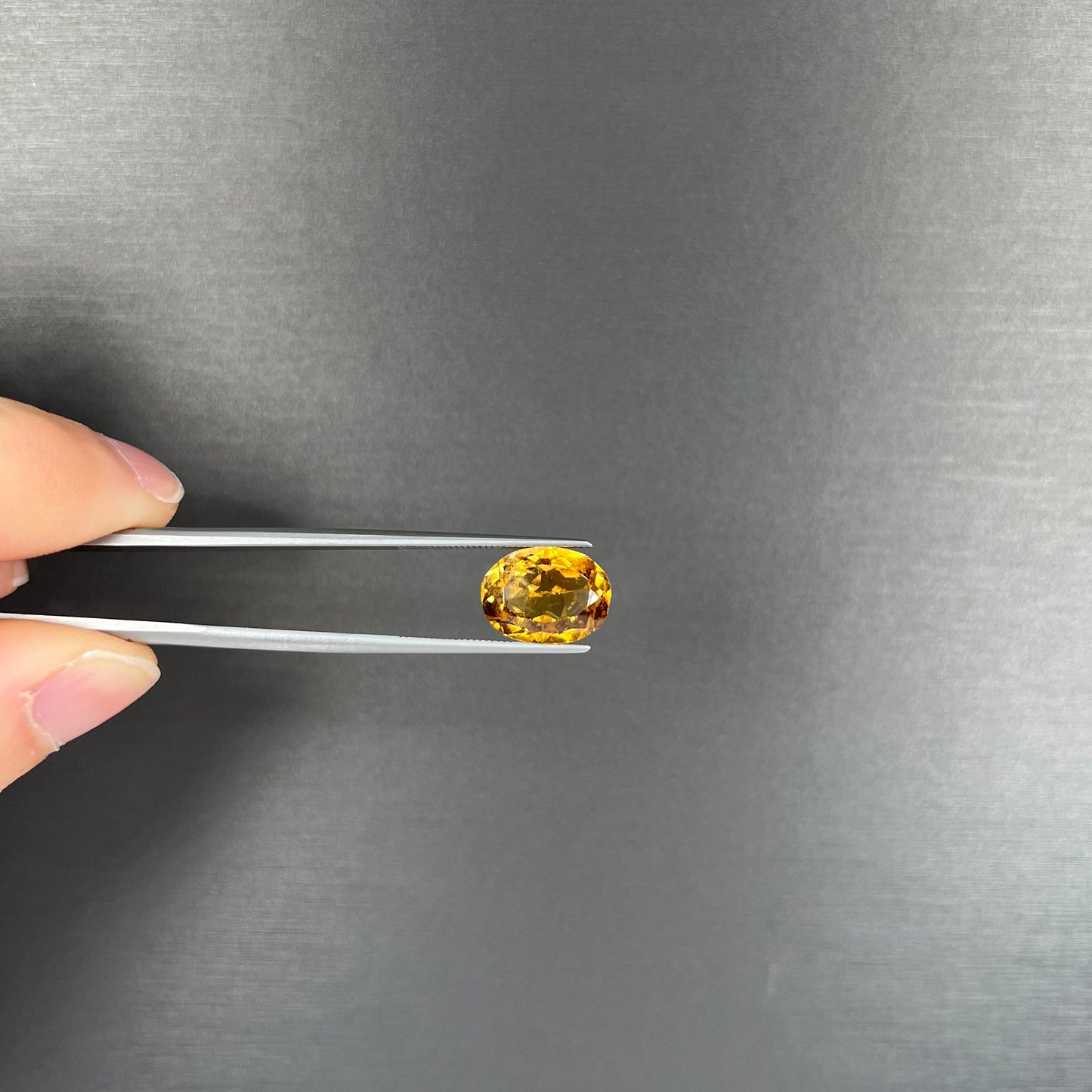 A loose, oval cut citrine gemstone. The stone is heavily included and roughly cut.